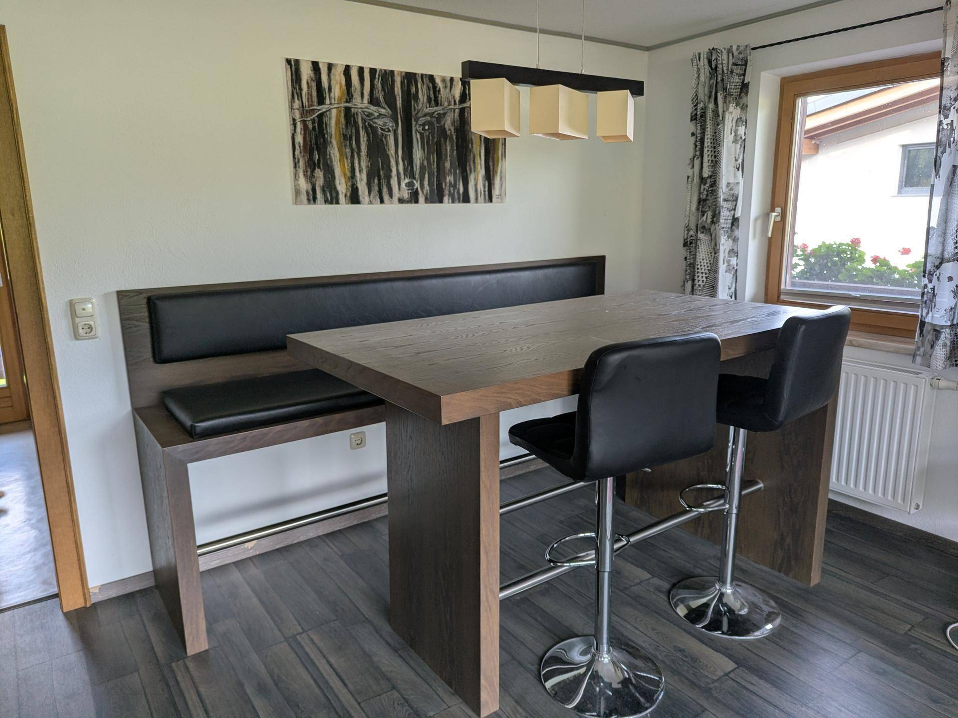 Gemütlicher Essbereich mit Holztisch, Sitzbank und Barhockern, ideal für gemeinsame Mahlzeiten.