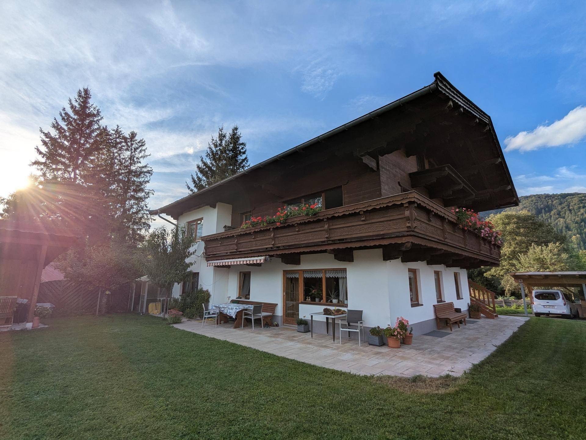Hausansicht vom Garten mit möblierter Terrasse und Blick auf die umliegende Natur.