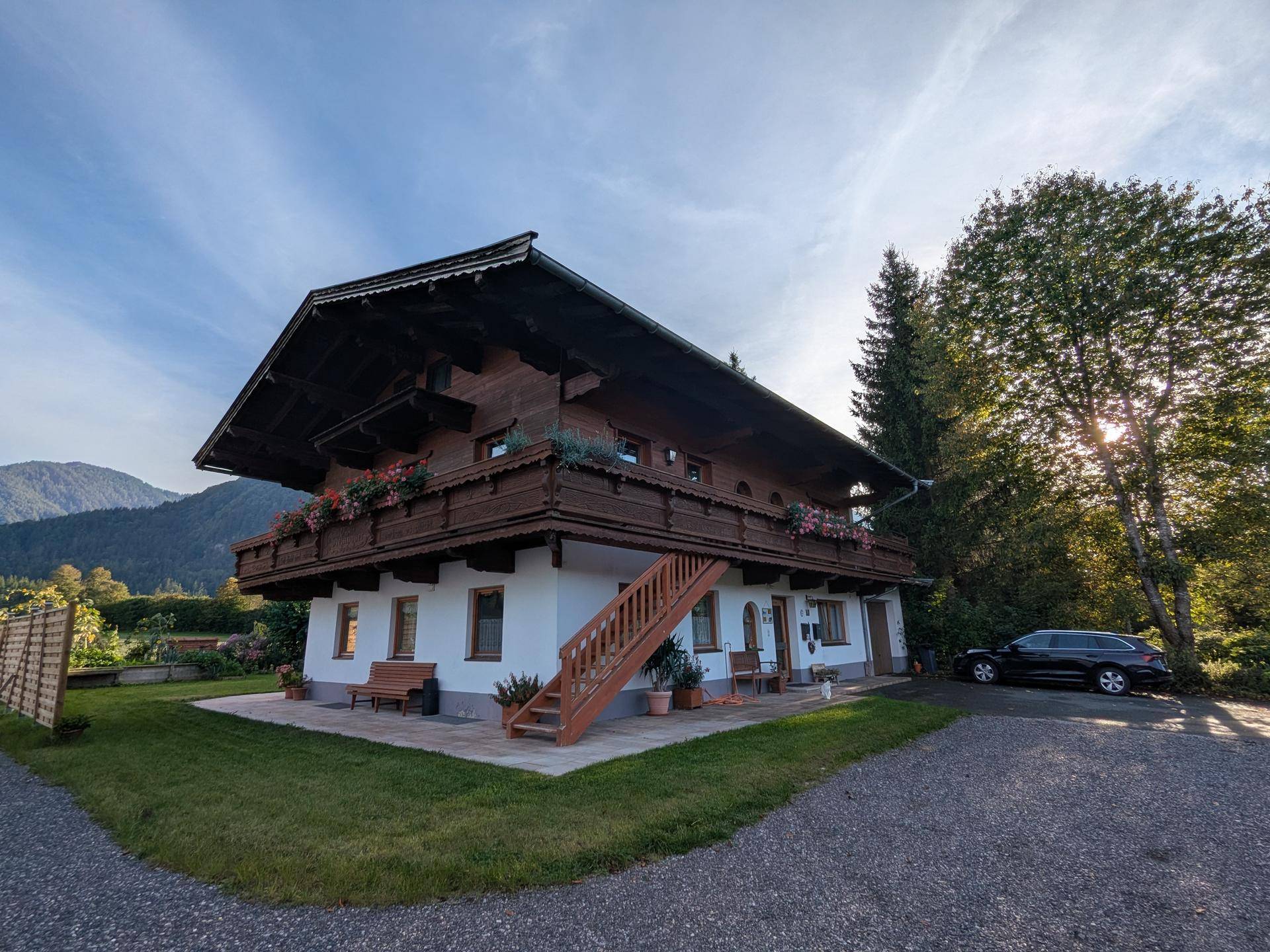 Traditionelles Alpenhaus mit Holzbalkonen, weißer Fassade und gepflegtem Vorgarten.