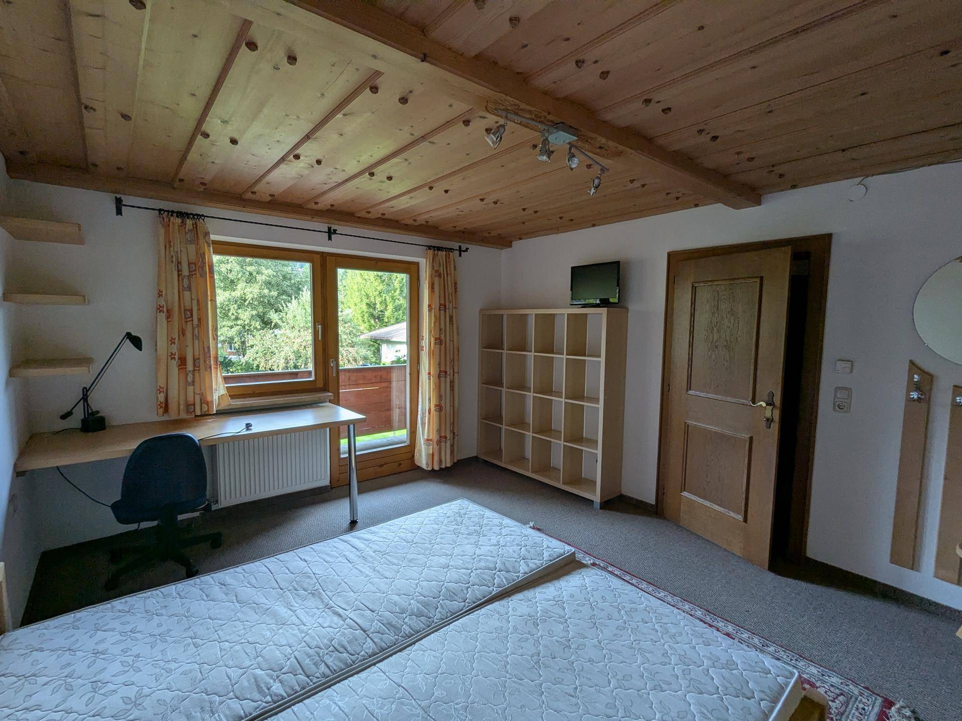 Helles Schlafzimmer mit zwei Betten, Schreibtisch und direktem Zugang zum Balkon.