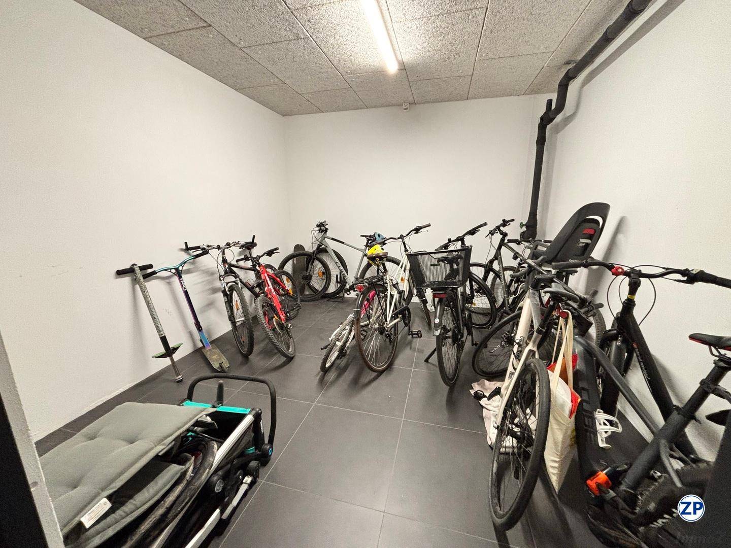 Gemeinschaftlicher Fahrradraum mit vielen Fahrrädern und Rollern.