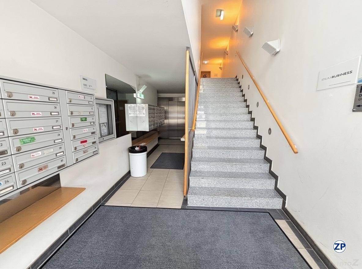 Eingangsbereich eines Gebäudes mit Briefkästen, Treppenhaus und Aufzug im Hintergrund.