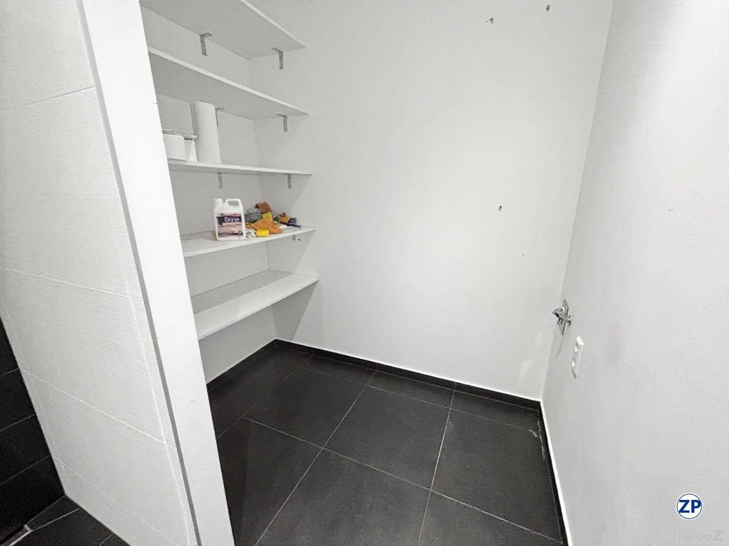Praktischer Abstellraum mit Regalen und dunklen Bodenfliesen für zusätzlichen Stauraum.