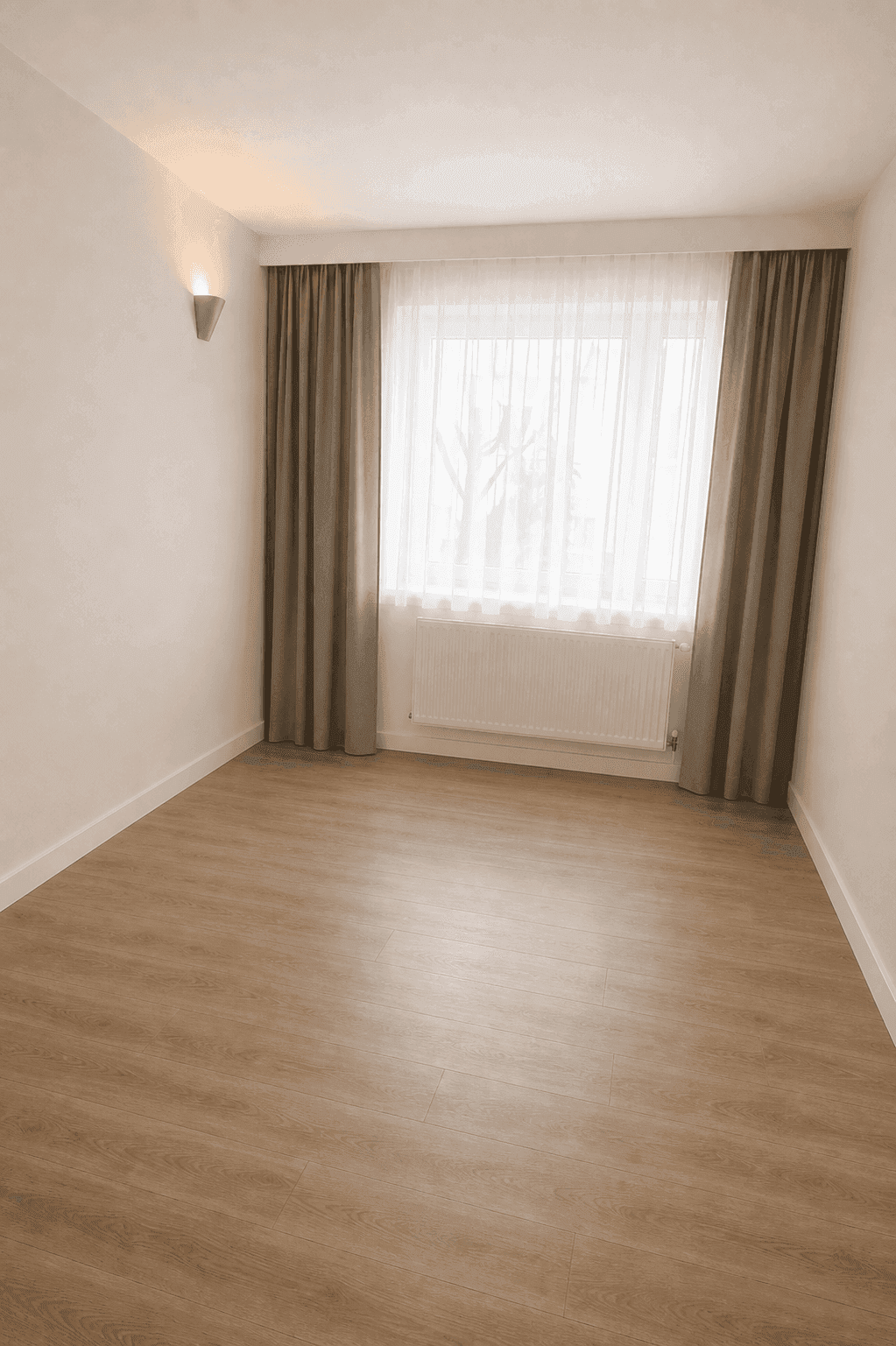 Heller Raum mit Laminatboden, großem Fenster und Vorhängen, ideal als Schlaf- oder Arbeitszimmer.