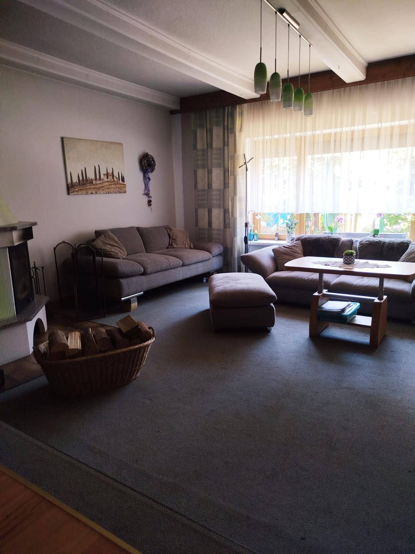 Geräumiges Wohnzimmer mit Kamin, bequemen Sofas und großen Fenstern für viel Tageslicht.