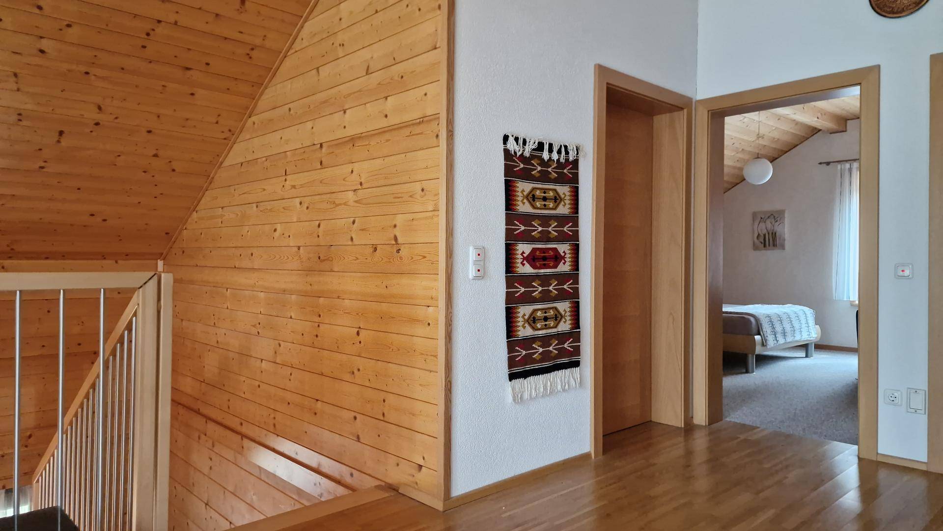 Heller Flur im Obergeschoss mit Holzverkleidung und Zugang zu den Schlafzimmern.
