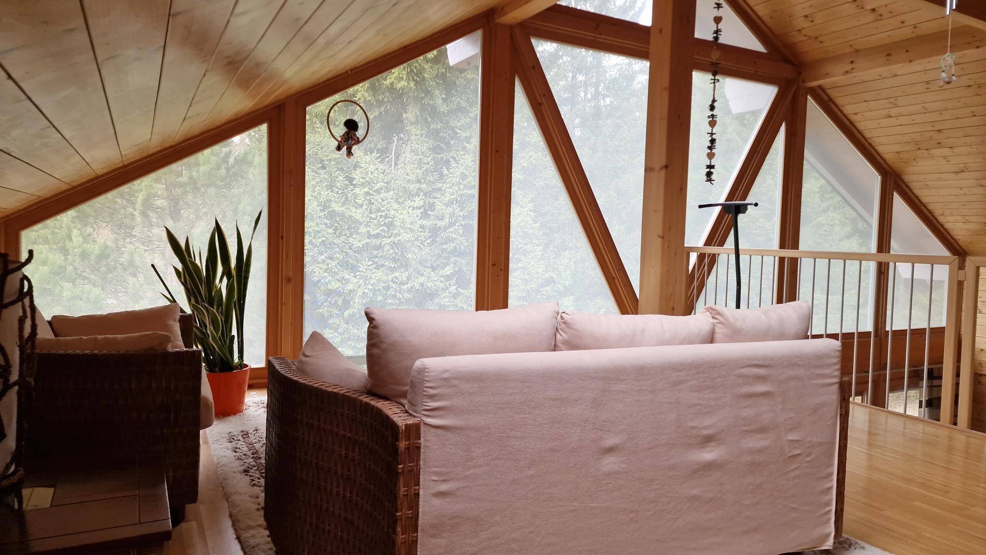 Gemütlicher Sitzbereich auf der Galerie mit Blick ins Grüne durch große Fenster und Holzverkleidung.