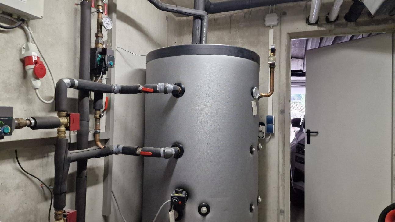 Hauswirtschaftsraum mit großem Warmwasserspeicher und sichtbaren Installationen, ideal für Technik und Lagerung.