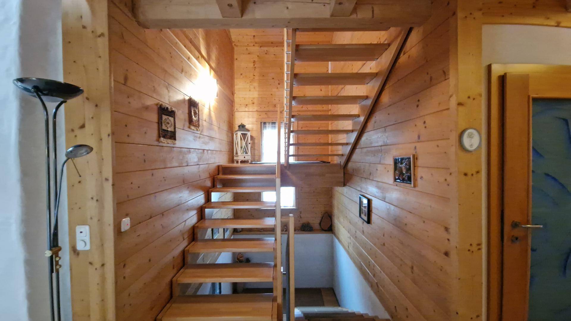 Rustikales Treppenhaus mit Holzvertäfelung an den Wänden und Holzstufen.