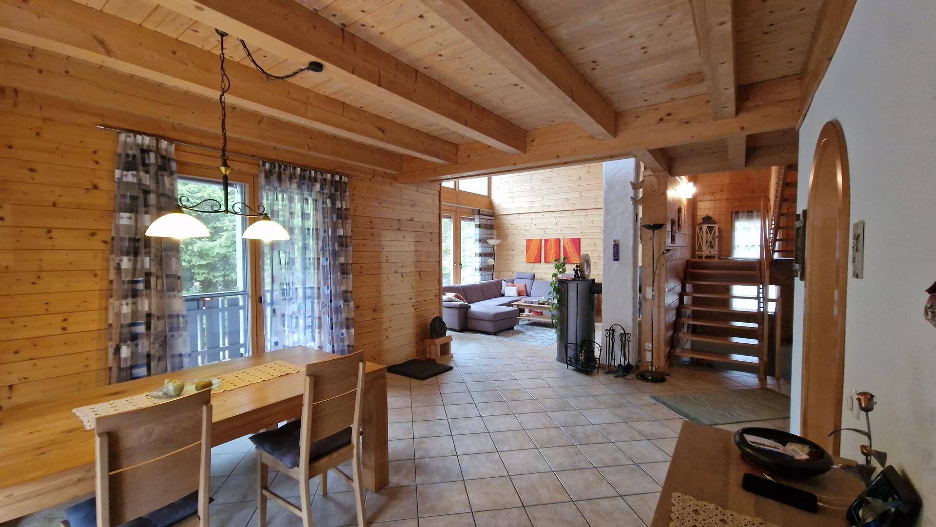 Rustikaler Wohn- und Essbereich mit Holzbalkendecke, Fliesenboden und Kaminofen.