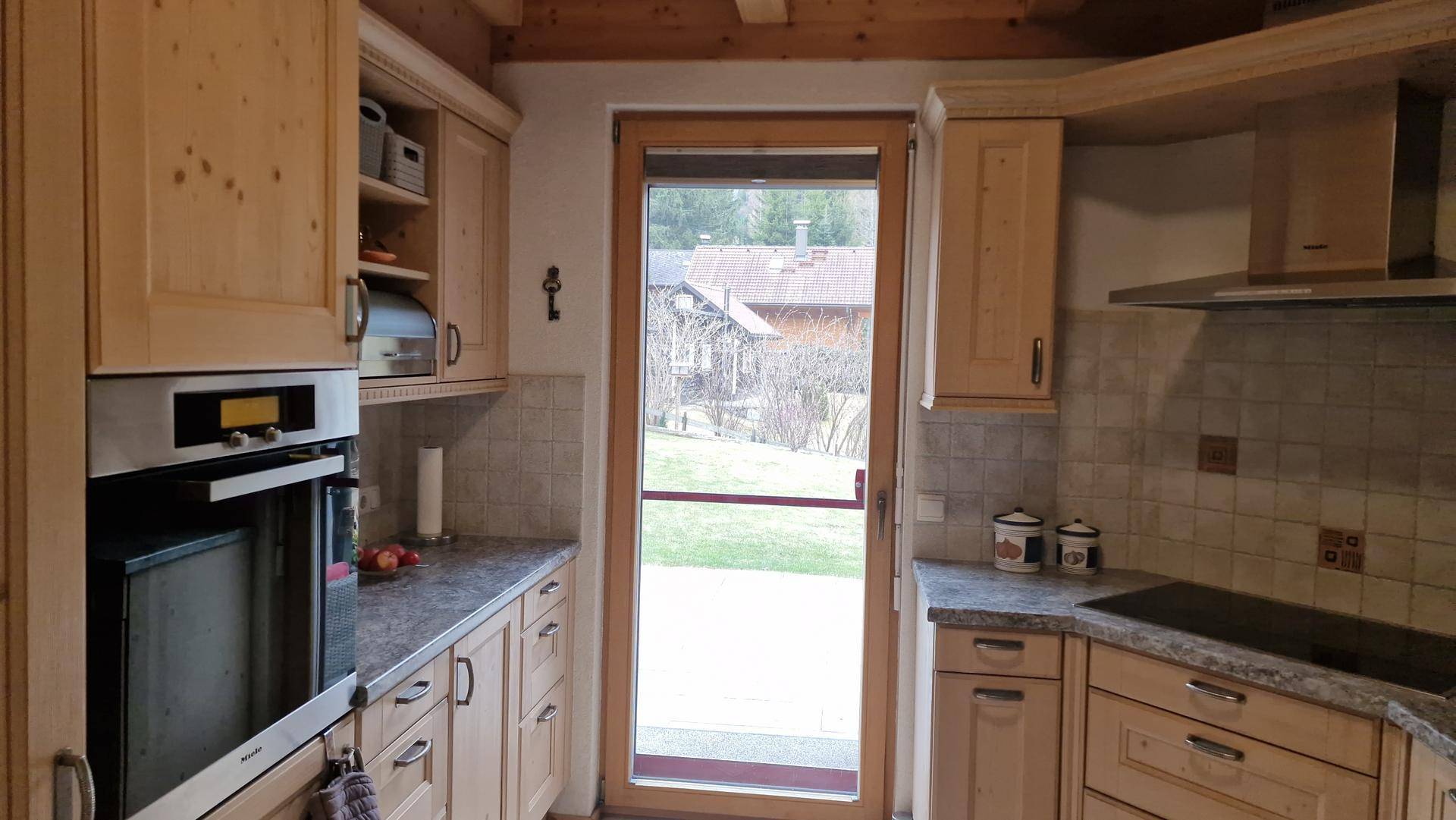 Traditionelle Holzküche mit Einbauofen und direktem Zugang zum Gartenbereich.