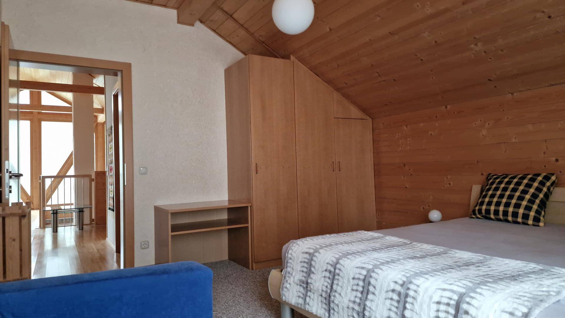 Gemütliches Schlafzimmer im Dachgeschoss mit Holzverkleidung und schrägen Wänden.