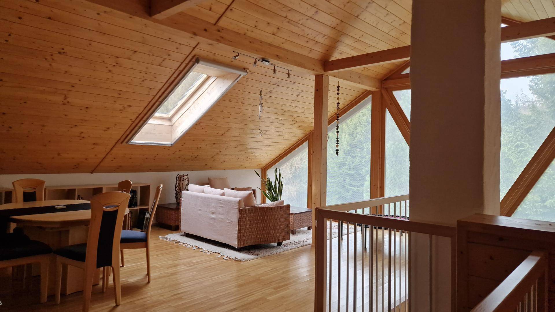 Offener Wohn- und Essbereich im Dachgeschoss mit Holzboden und Dachfenster.