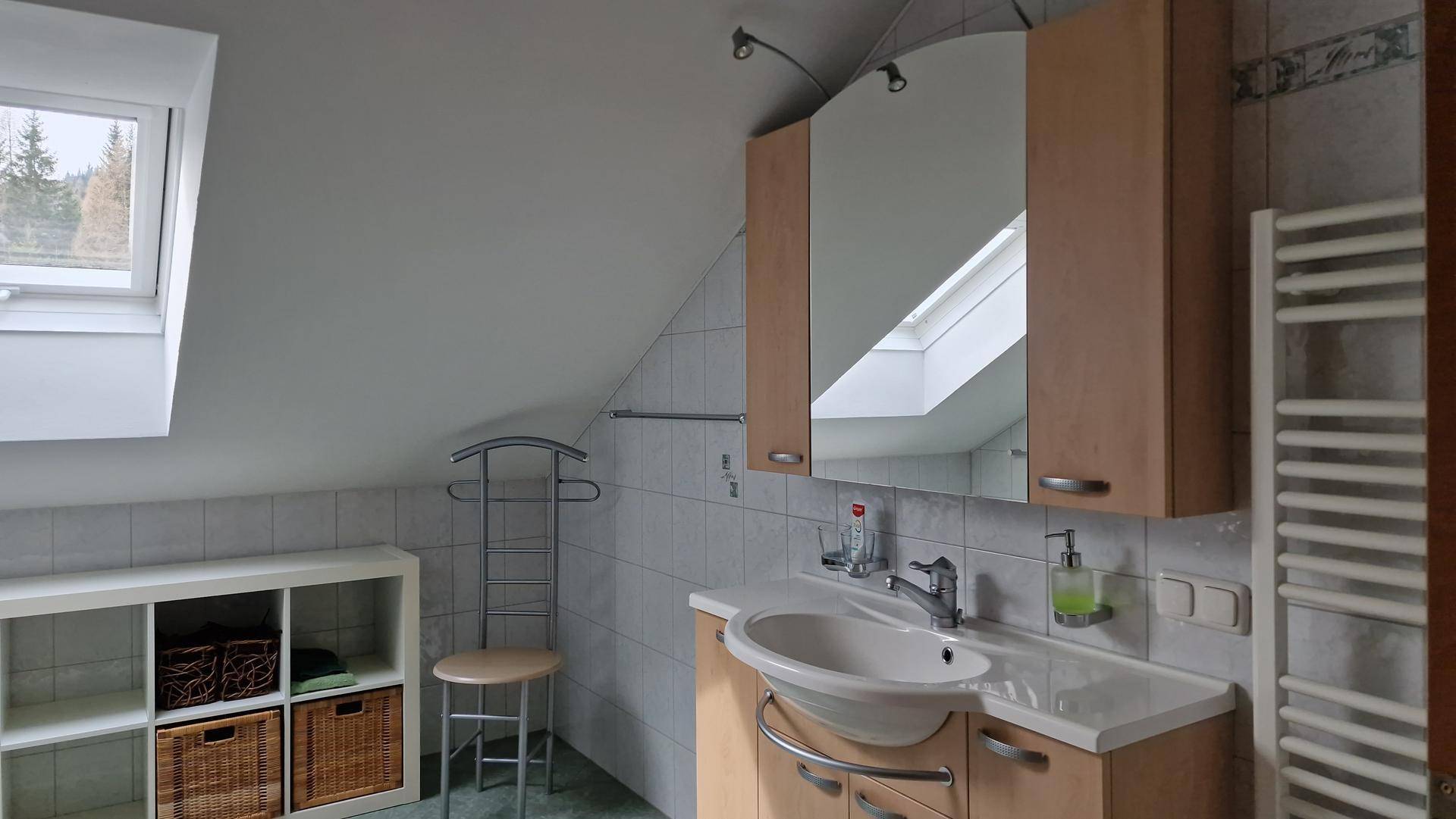 Helles Badezimmer im Dachgeschoss mit Dachfenster, Waschtisch und Handtuchheizkörper.