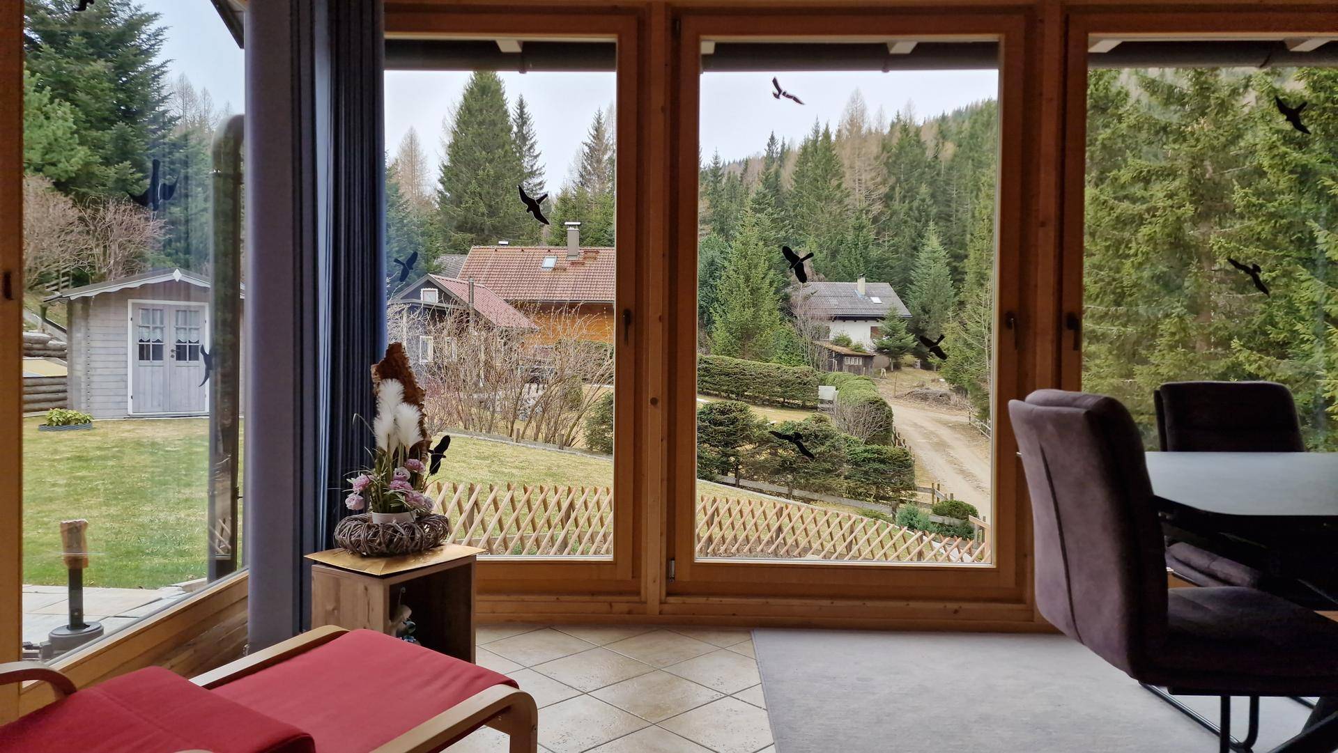 Heller Wintergarten mit großen Fenstern und weitem Blick auf die bewaldete Umgebung.