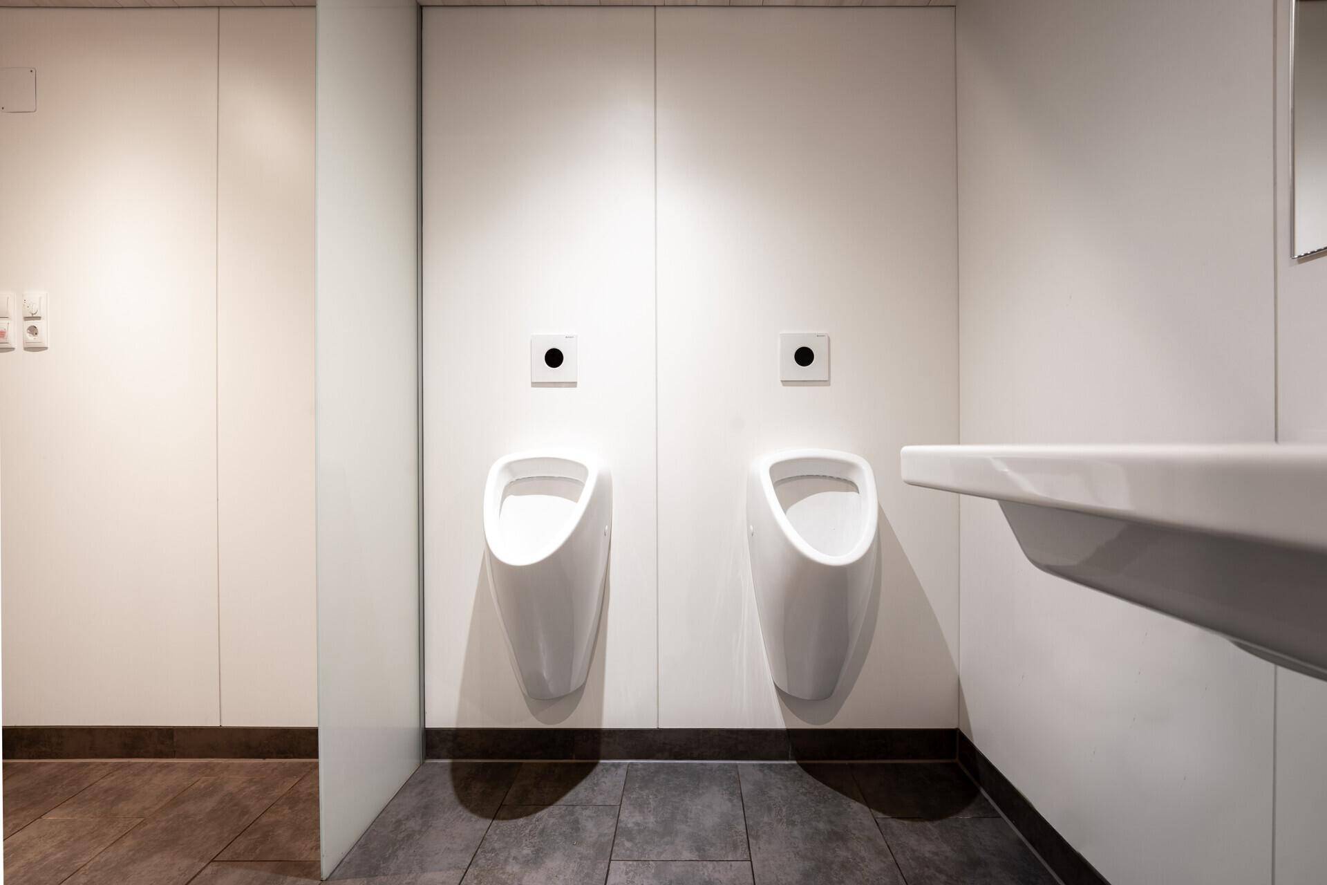 Sauberer und funktionaler Herrenwaschraum mit zwei Urinalen und einem Waschbecken, in modernem Design.