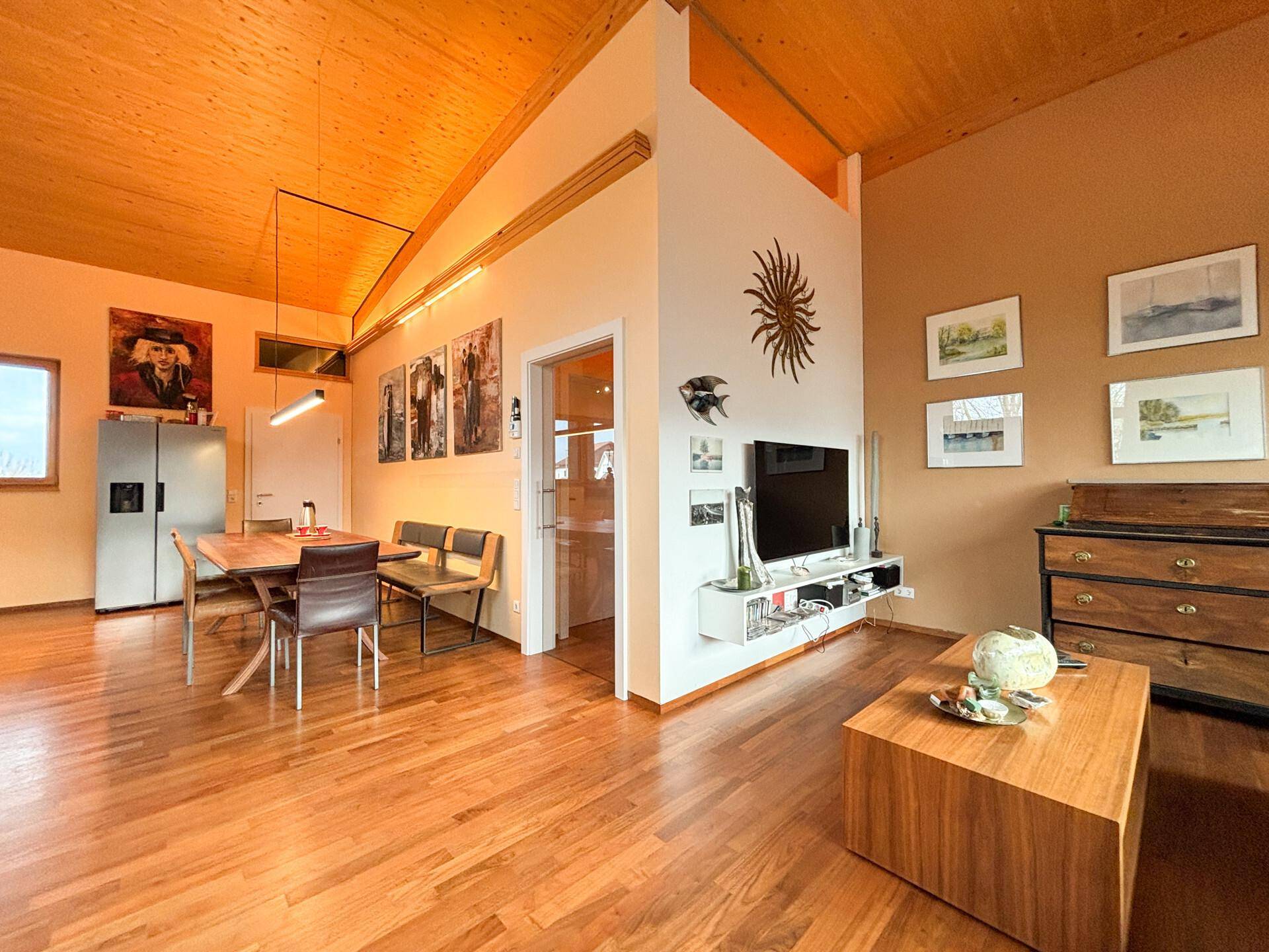 Geräumiger Wohn- und Essbereich mit Holzboden, hoher Decke und moderner Einrichtung.
