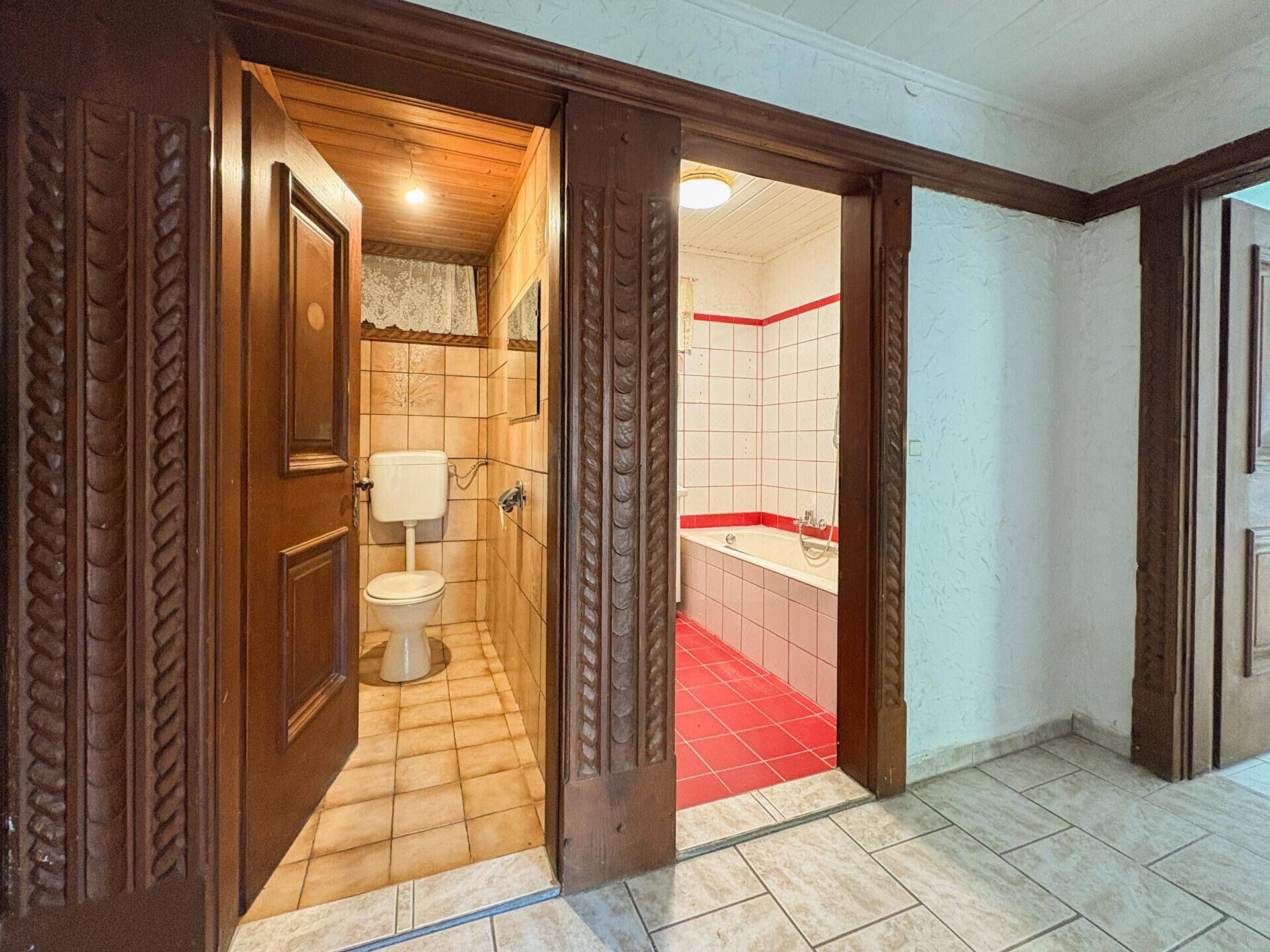 Flur mit Zugang zu einem WC und einem Badezimmer, beide mit traditionellen Fliesen.