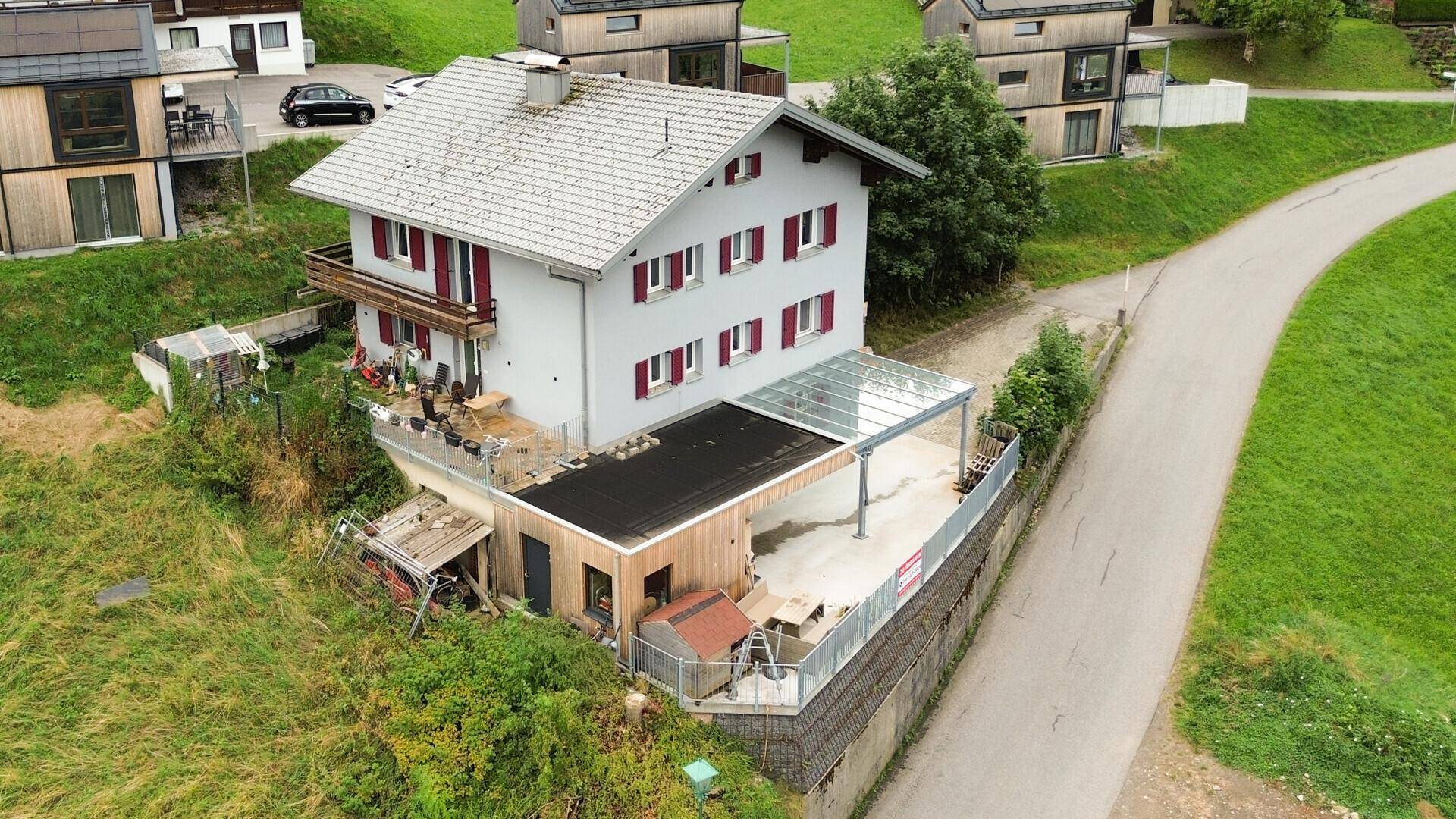 Ansicht des Hauses von oben mit Balkon, Carport und der umliegenden ländlichen Umgebung.