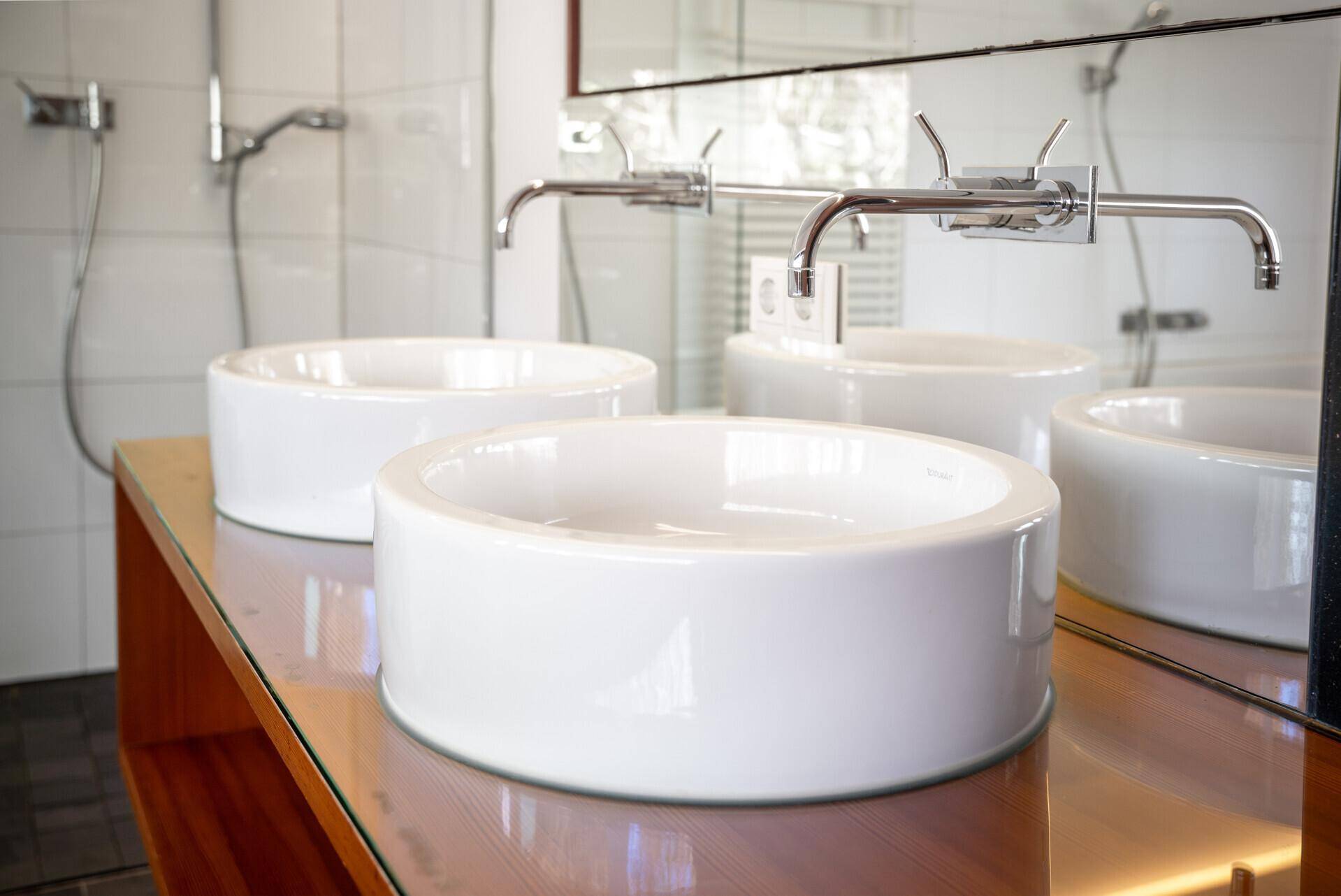 Detailaufnahme der modernen Doppelwaschbecken auf einer Holzablage im Badezimmer.