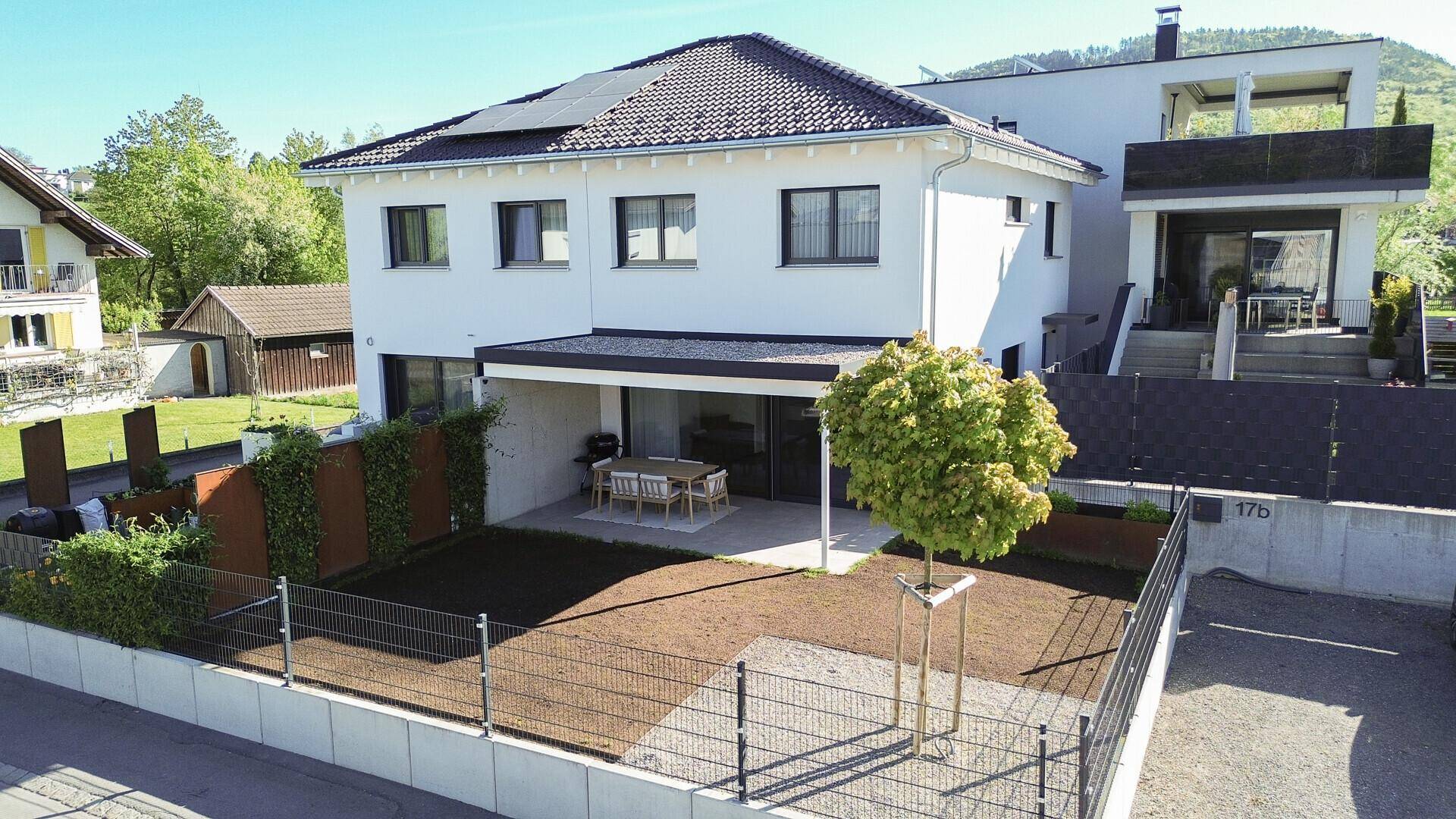 Modernes Einfamilienhaus mit Solaranlage auf dem Dach, Garten und überdachter Terrasse.