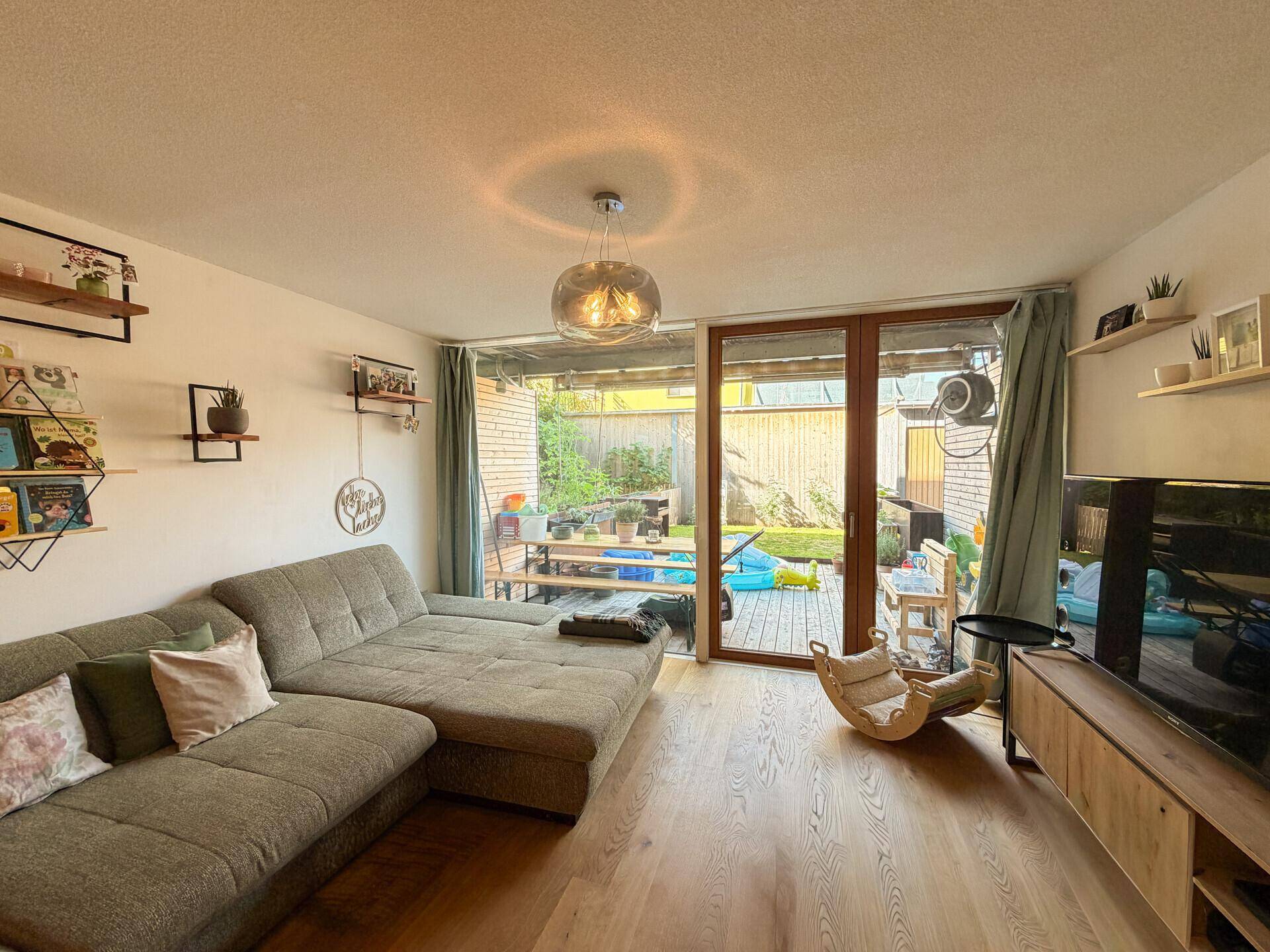 Gemütliches Wohnzimmer mit großem Sofa, Holzboden und direktem Zugang zum Garten.