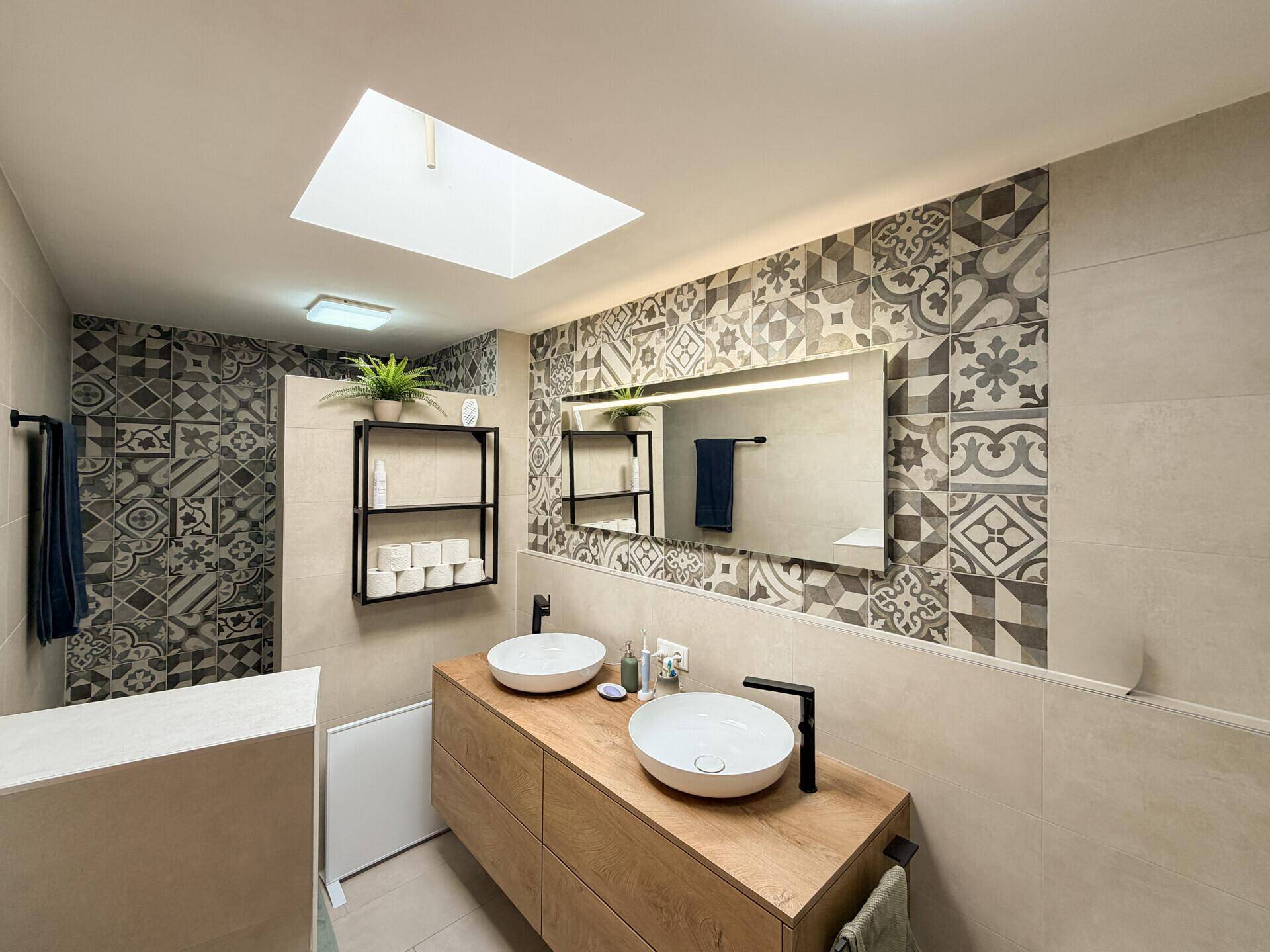 Modernes Badezimmer mit Doppelwaschbecken, begehbarer Dusche und gemusterten Fliesen.