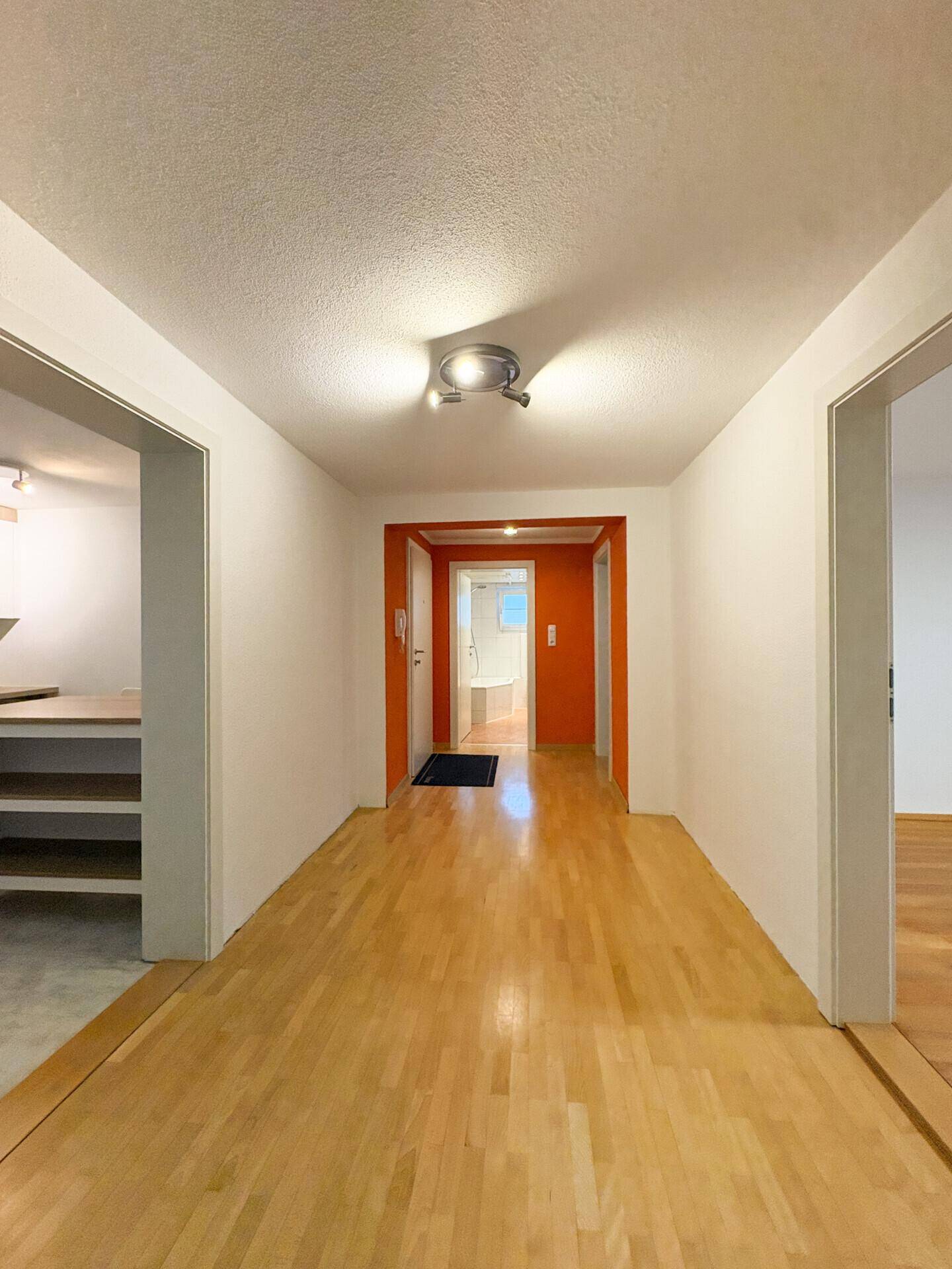 Langer Flur mit hellem Holzfußboden, der verschiedene Bereiche der Wohnung verbindet.