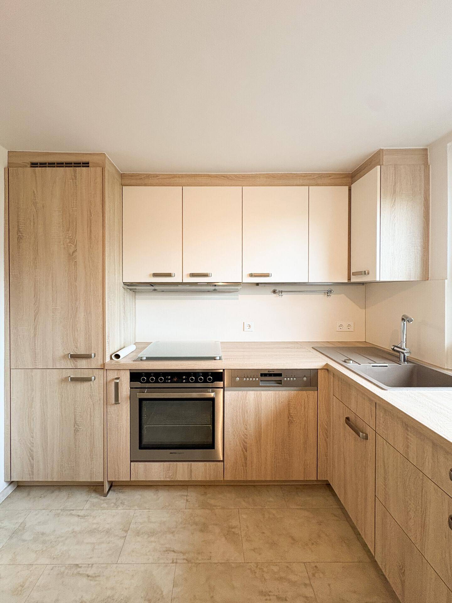 Funktionale Küche mit hellen Holzschränken, integriertem Backofen und Kochfeld.