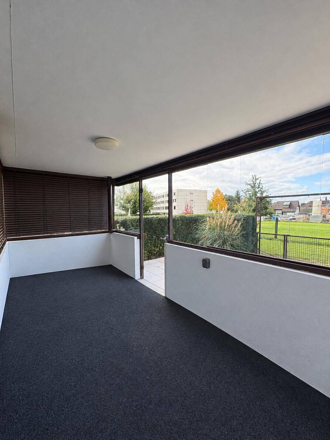 Verglaste Loggia mit Teppichboden und Ausblick auf die Umgebung.