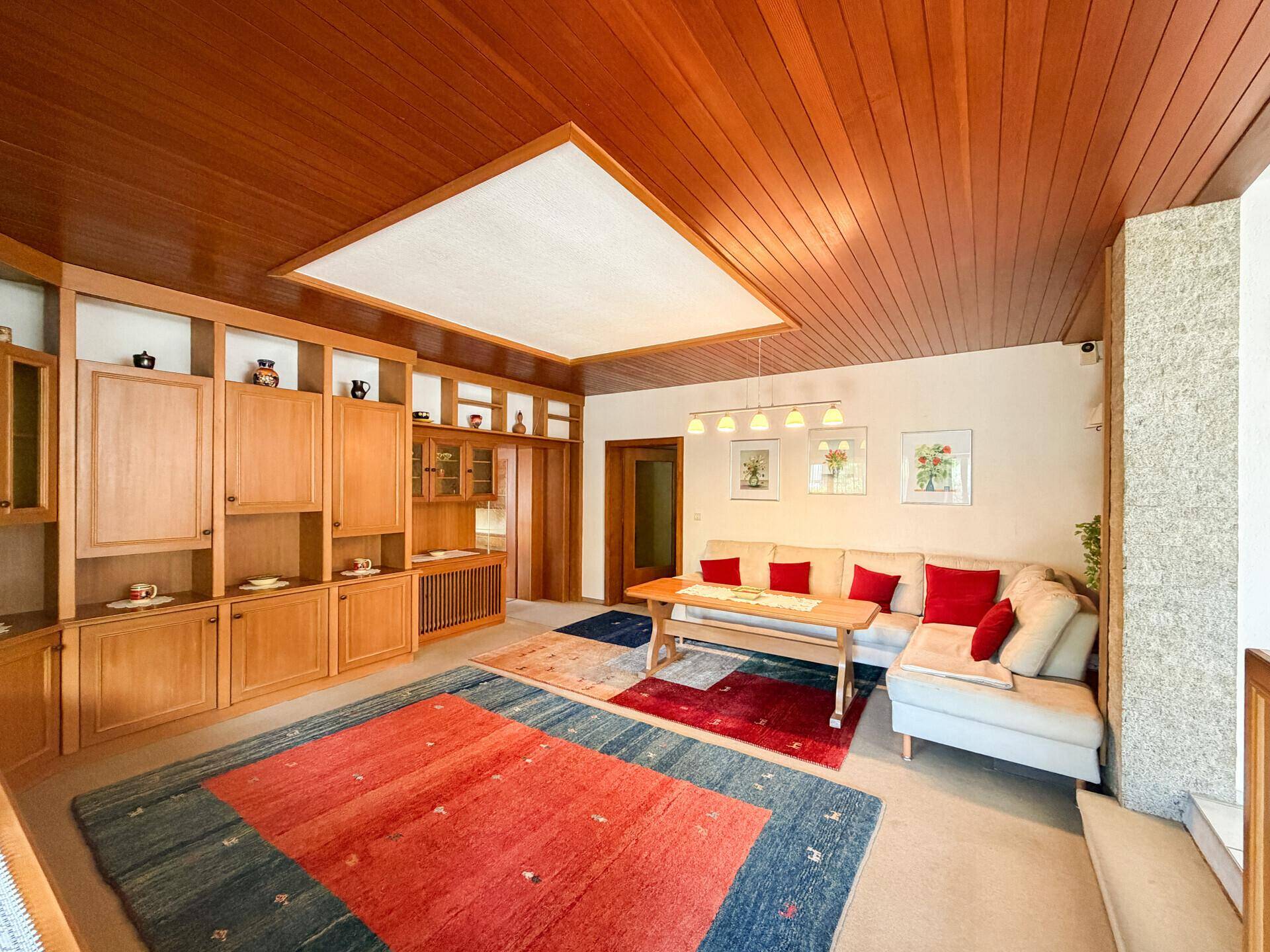 Geräumiges Wohnzimmer mit Holzdecke, integrierten Schränken und einem bequemen Ecksofa.