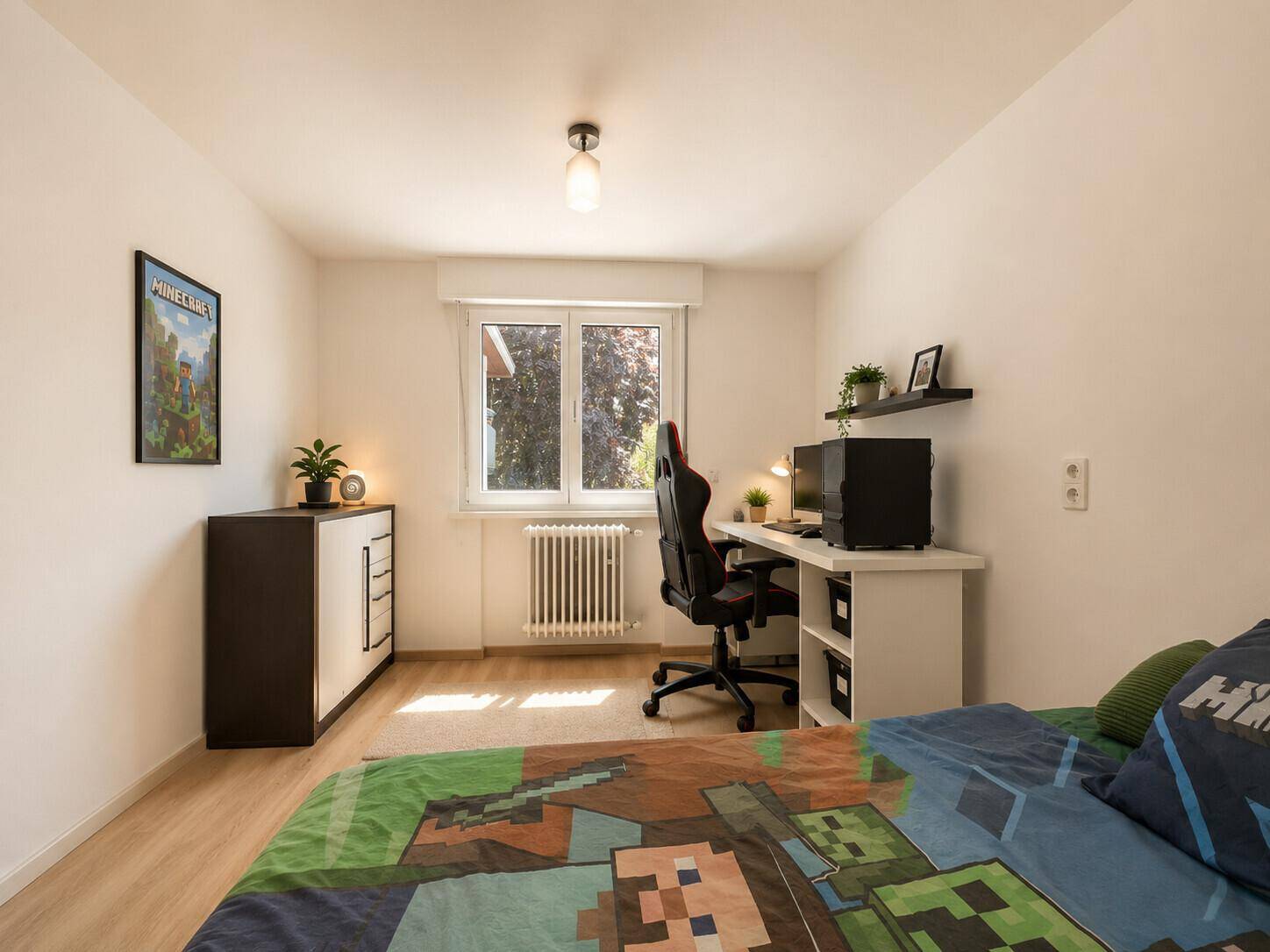 Jugendzimmer mit Schreibtisch, Gaming-Stuhl und einem Fenster, das den Raum gut beleuchtet.