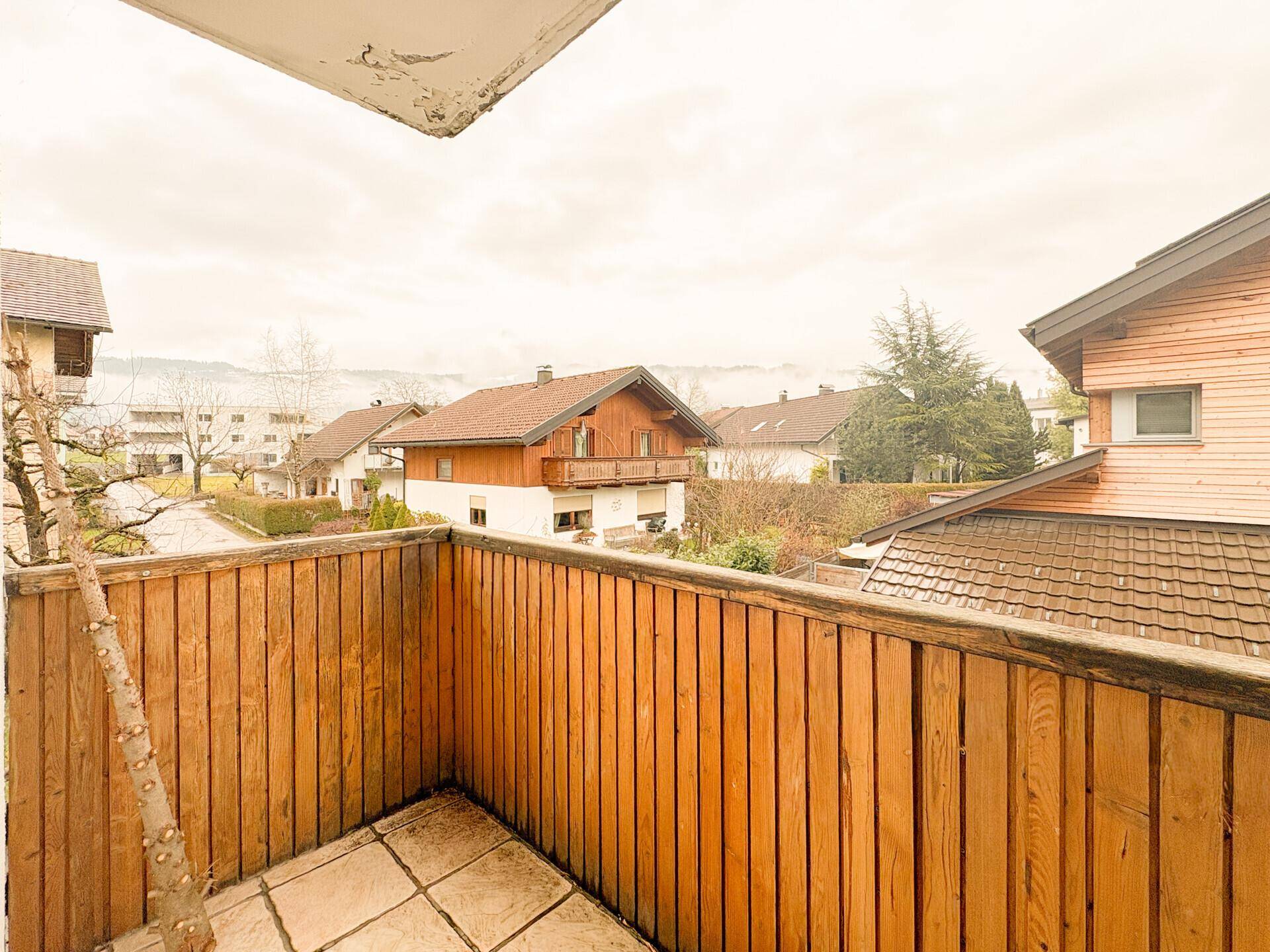 Kleiner Balkon mit Holzverkleidung und Blick auf die umliegenden Häuser.