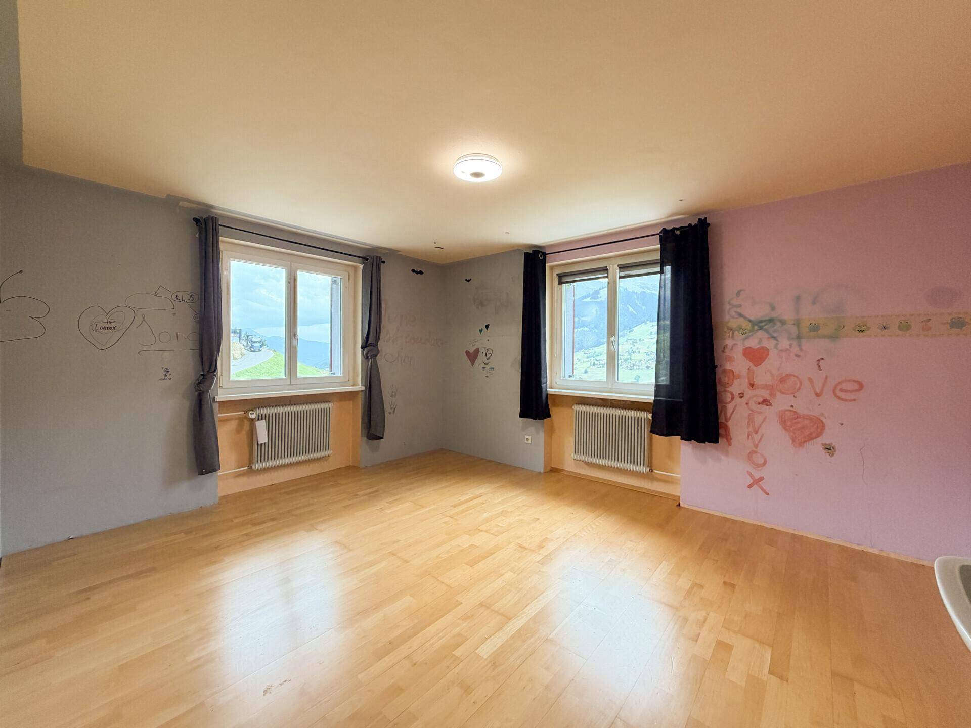 Farbenfrohes Kinderzimmer mit Holzboden und zwei Fenstern, ideal für kreative Entfaltung.