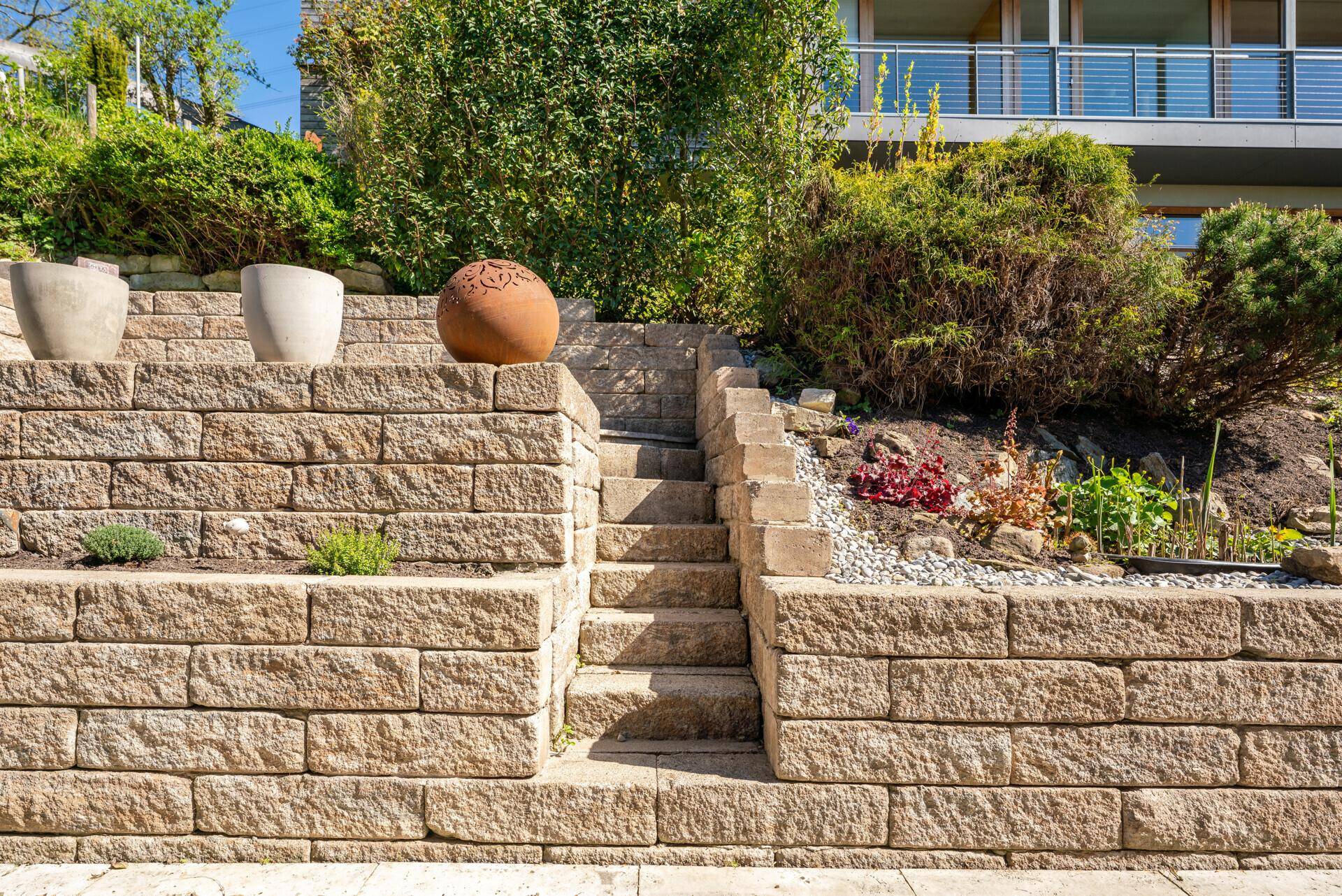 Detailansicht der terrassierten Steinmauern und Treppen im gepflegten Gartenbereich.