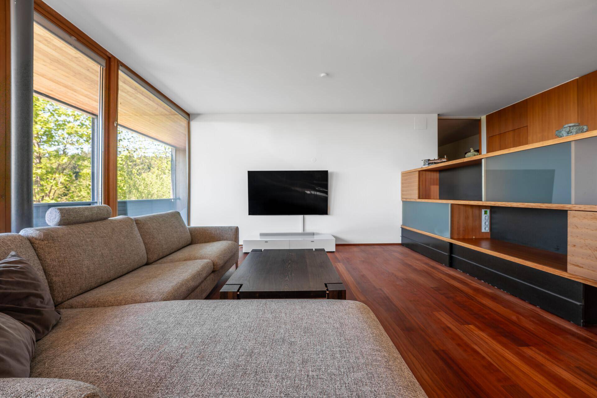 Modernes Wohnzimmer mit Holzboden, großem Sofa und integriertem Mediamöbel.