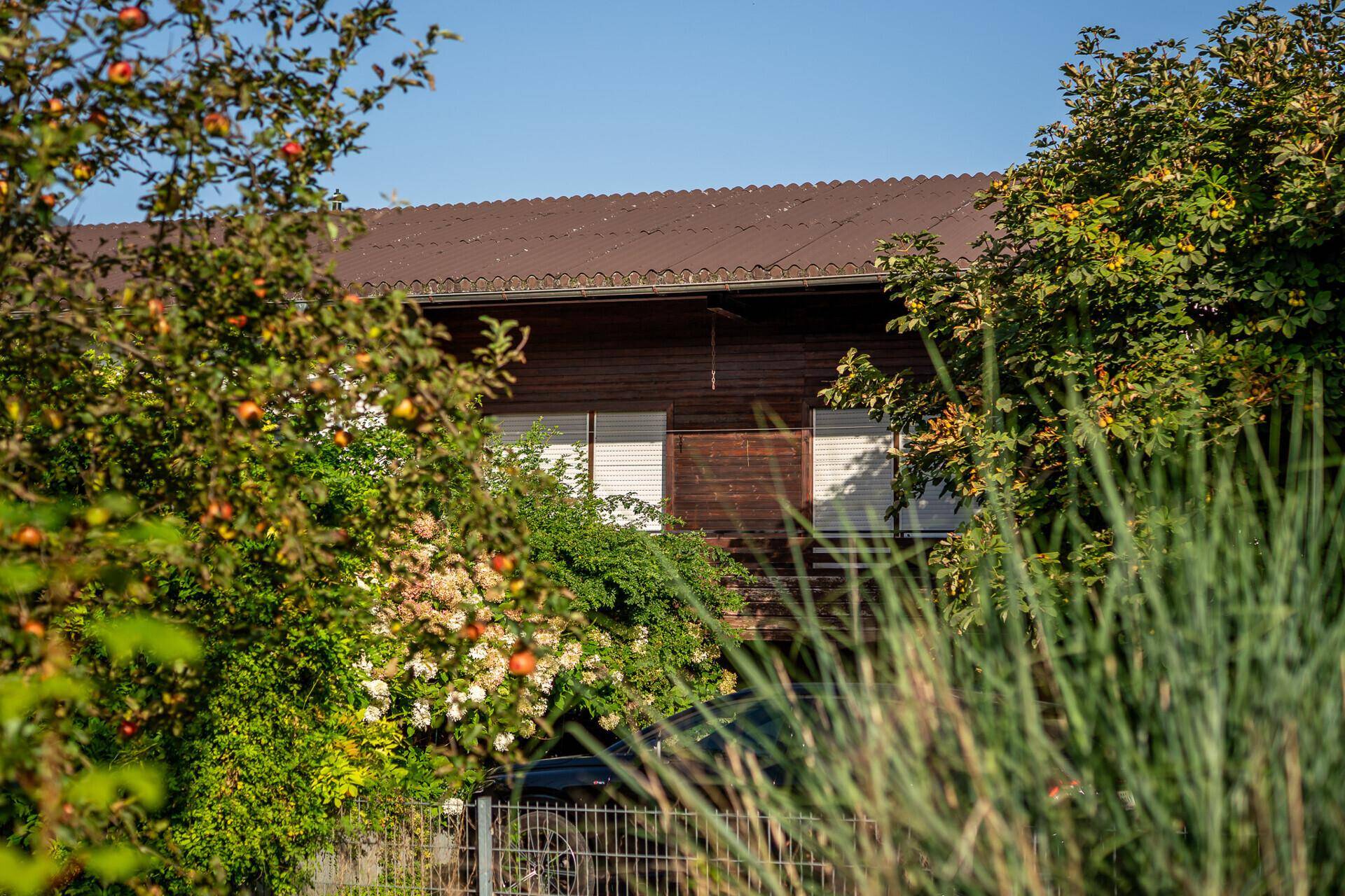 Teilansicht des Hauses, umgeben von üppigem Grün und Obstbäumen.