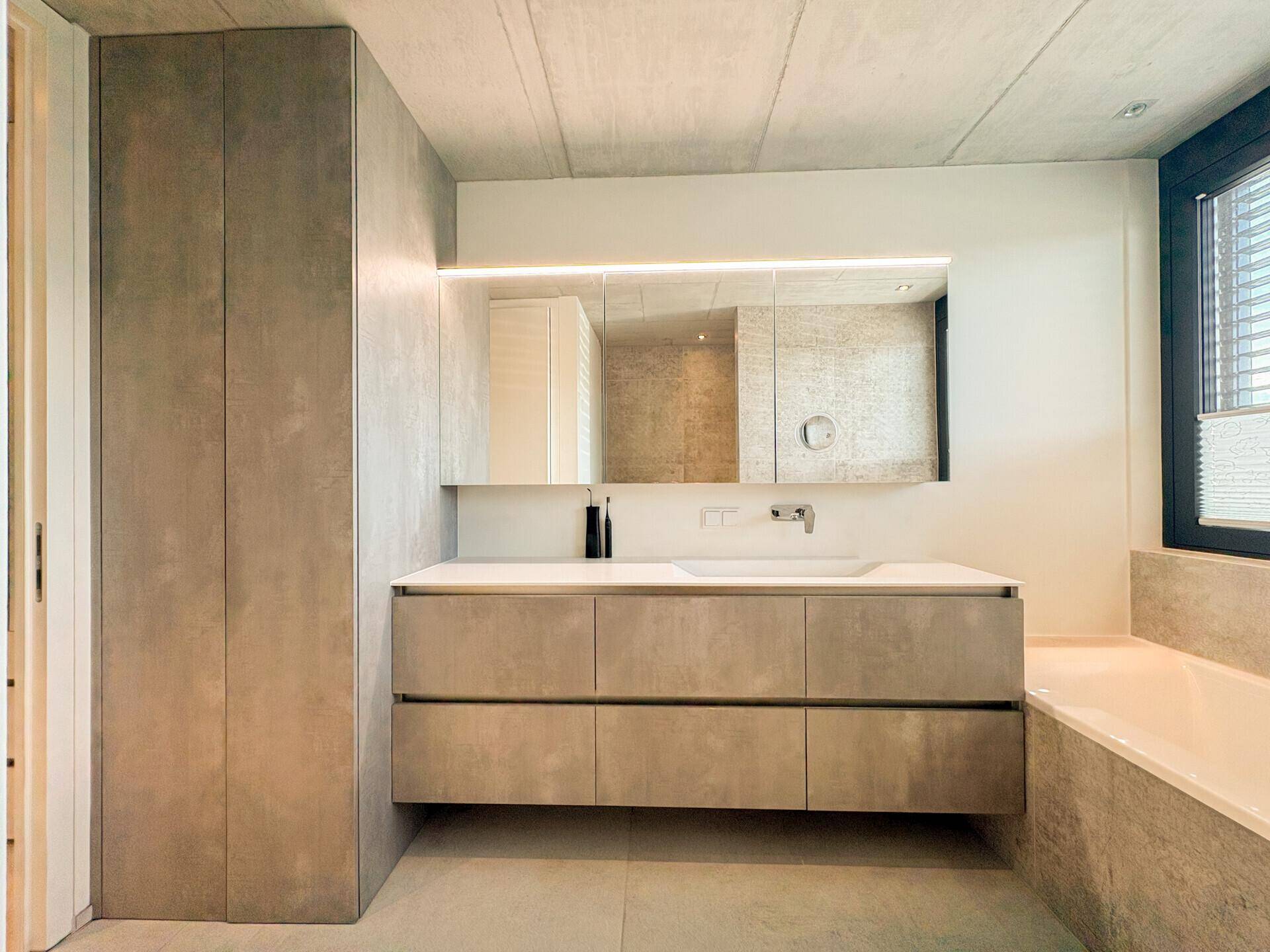 Modernes Badezimmer mit Doppelwaschbecken, Spiegelschrank und Badewanne.