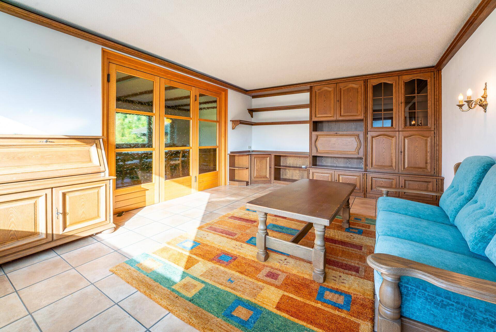Geräumiges Wohnzimmer mit Einbauschränken aus Holz und Zugang zu einem Außenbereich.