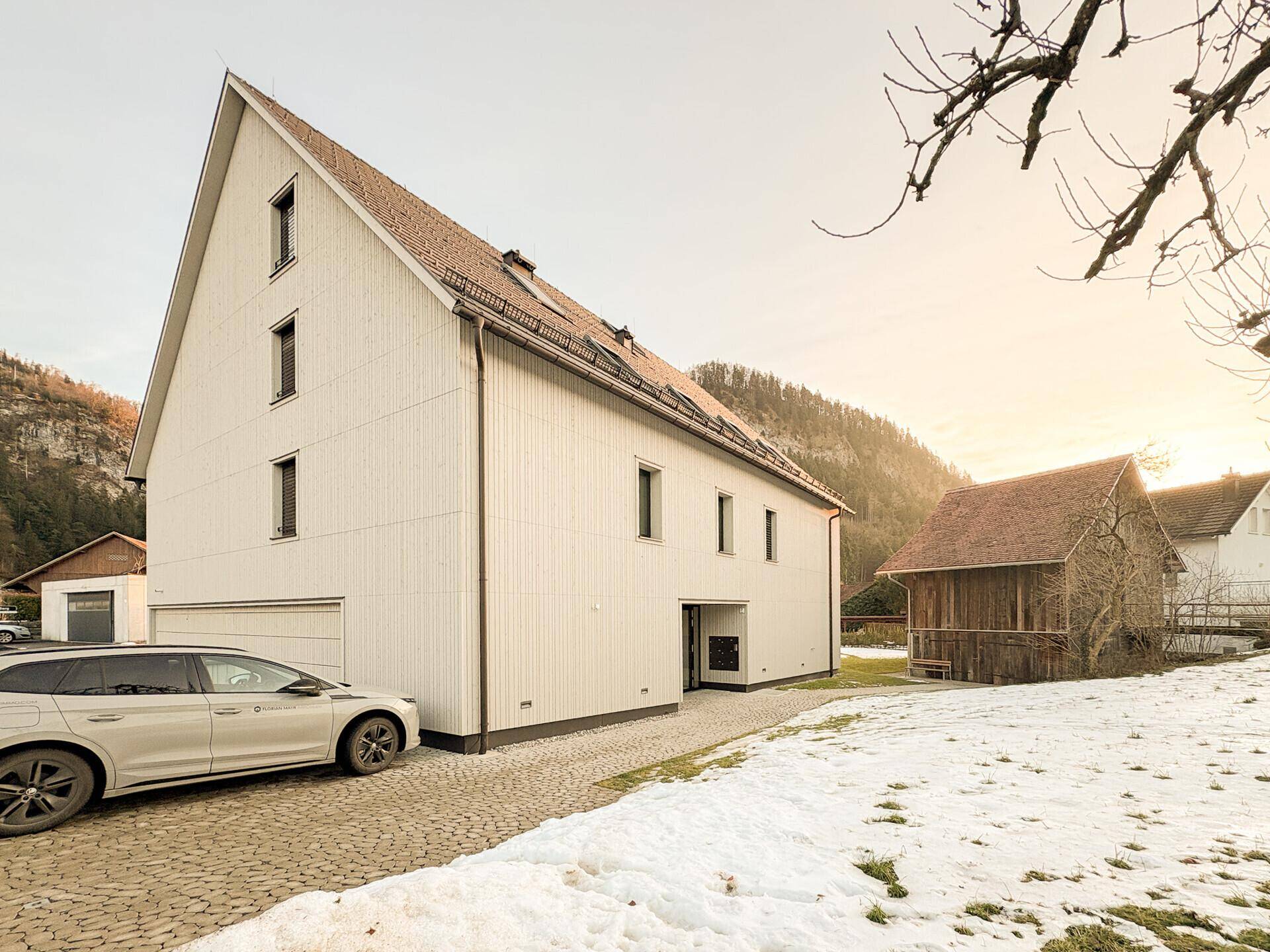 Seitenansicht des modernen Gebäudes mit Einfahrt und gepflastertem Parkplatz im Winter.