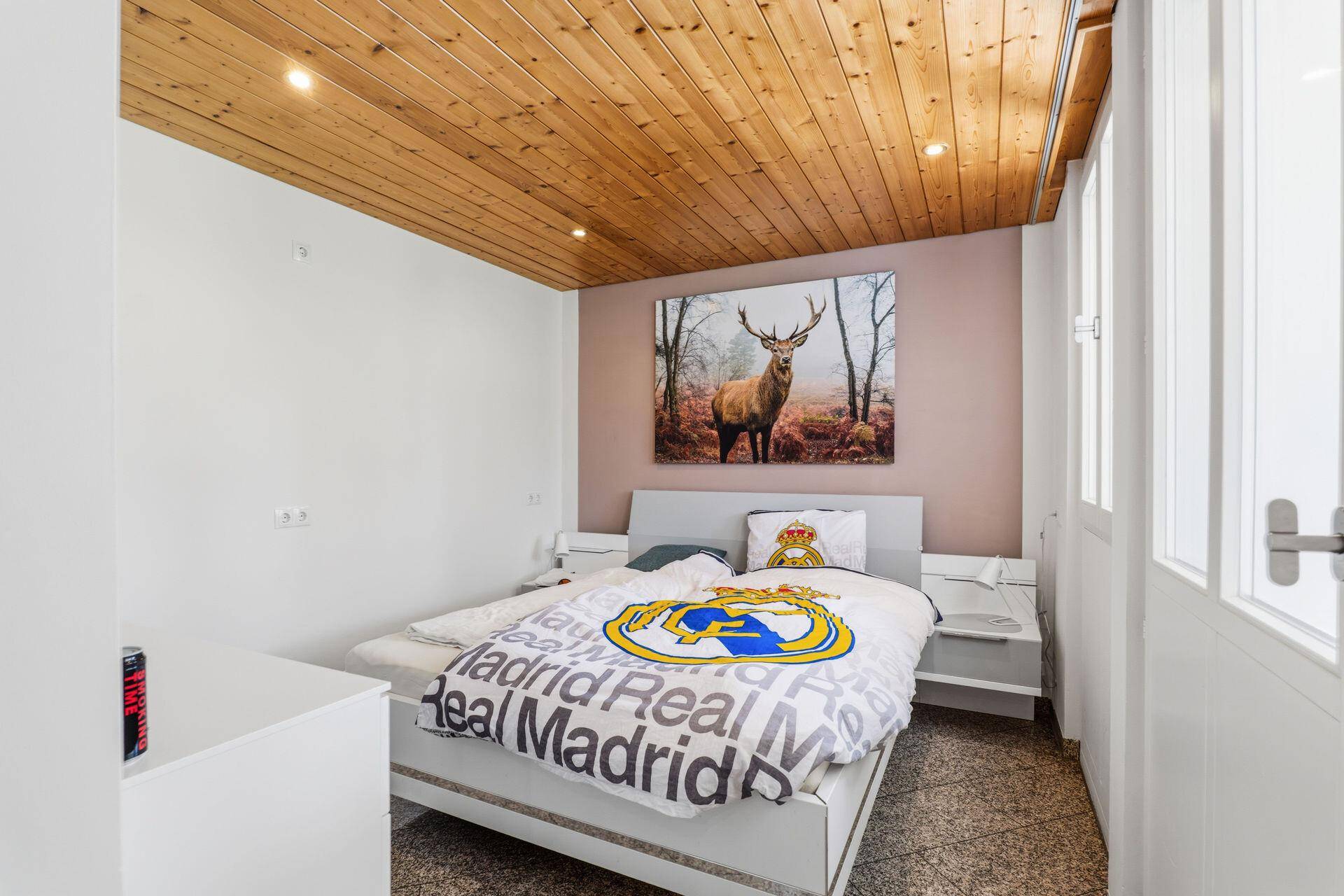 Kinderzimmer mit Holzdachschräge, Einzelbett und Hirschmotiv an der Wand.