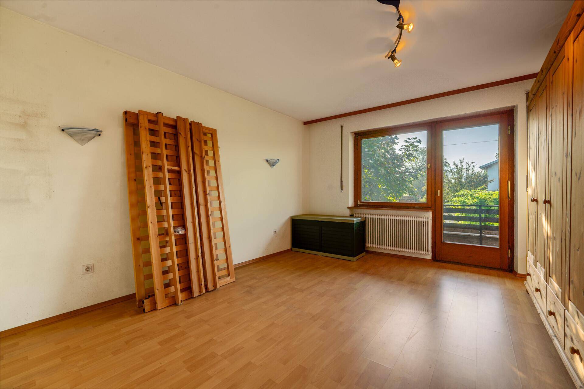 Leeres Schlafzimmer mit Holzboden und Balkonzugang, bereit zur individuellen Gestaltung.