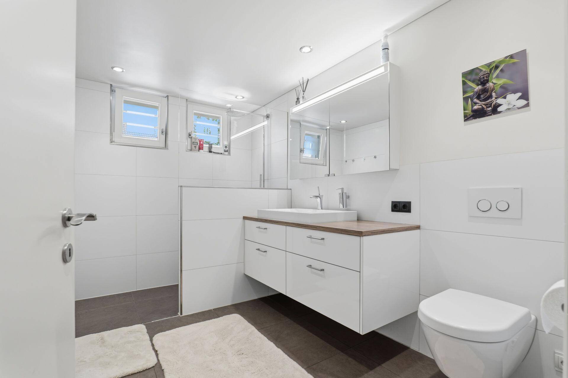 Modernes Badezimmer mit begehbarer Dusche, schwebendem Waschtisch und Spiegelschrank.