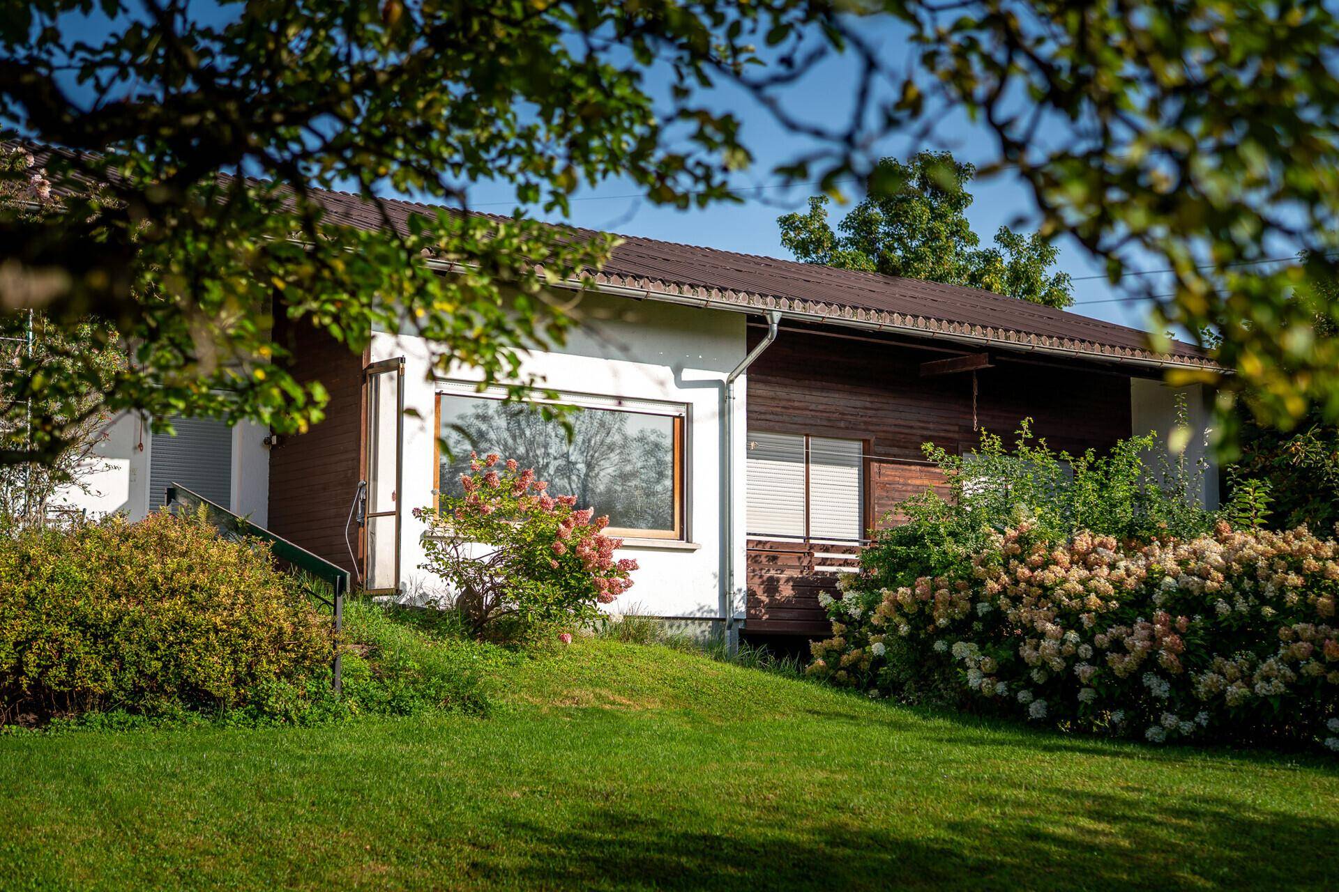 Seitenansicht des Hauses mit großer Fensterfront und gepflegtem Vorgarten.