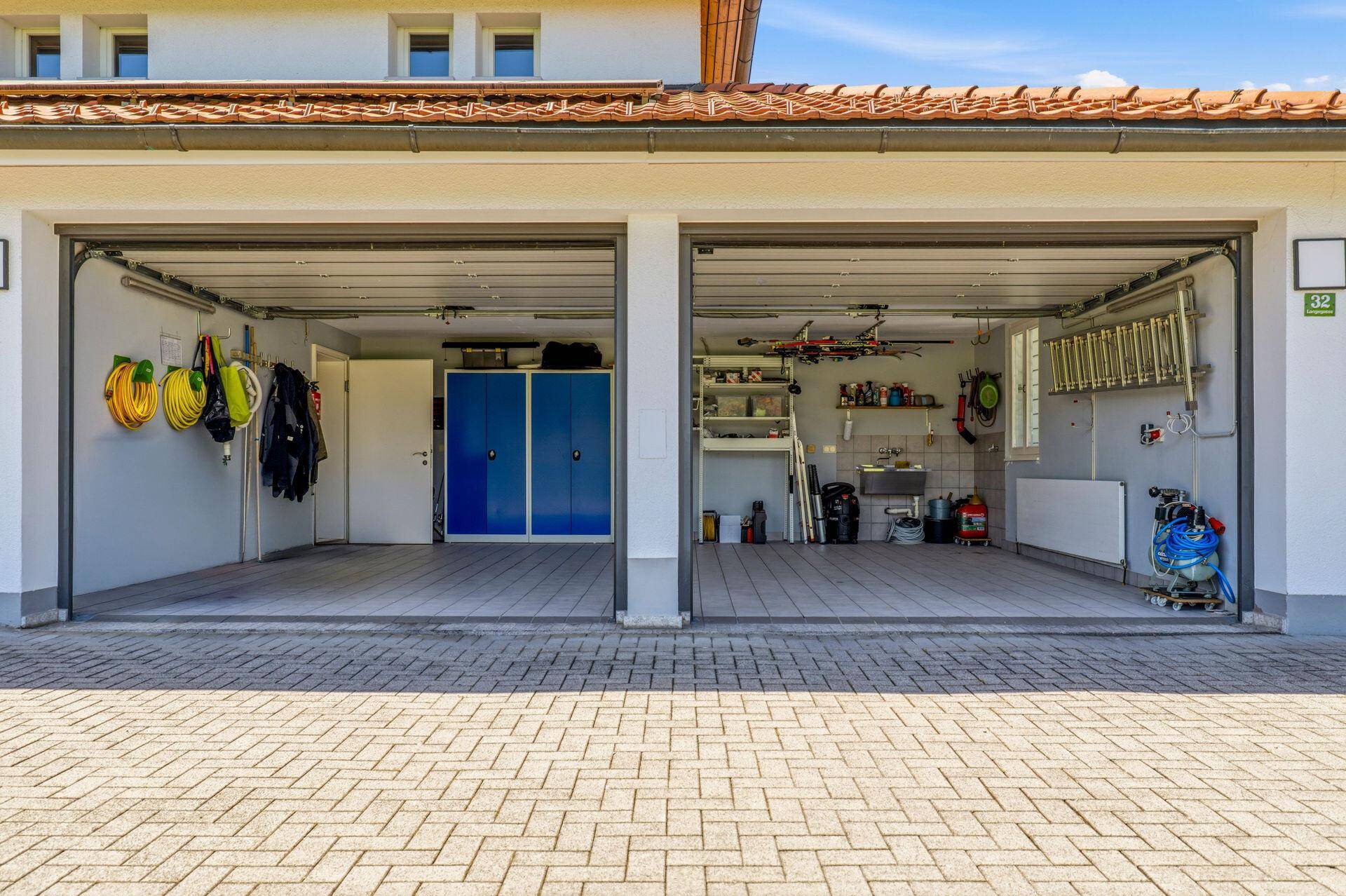 Doppelgarage mit zwei offenen Toren, gefliestem Boden und Stauraum.