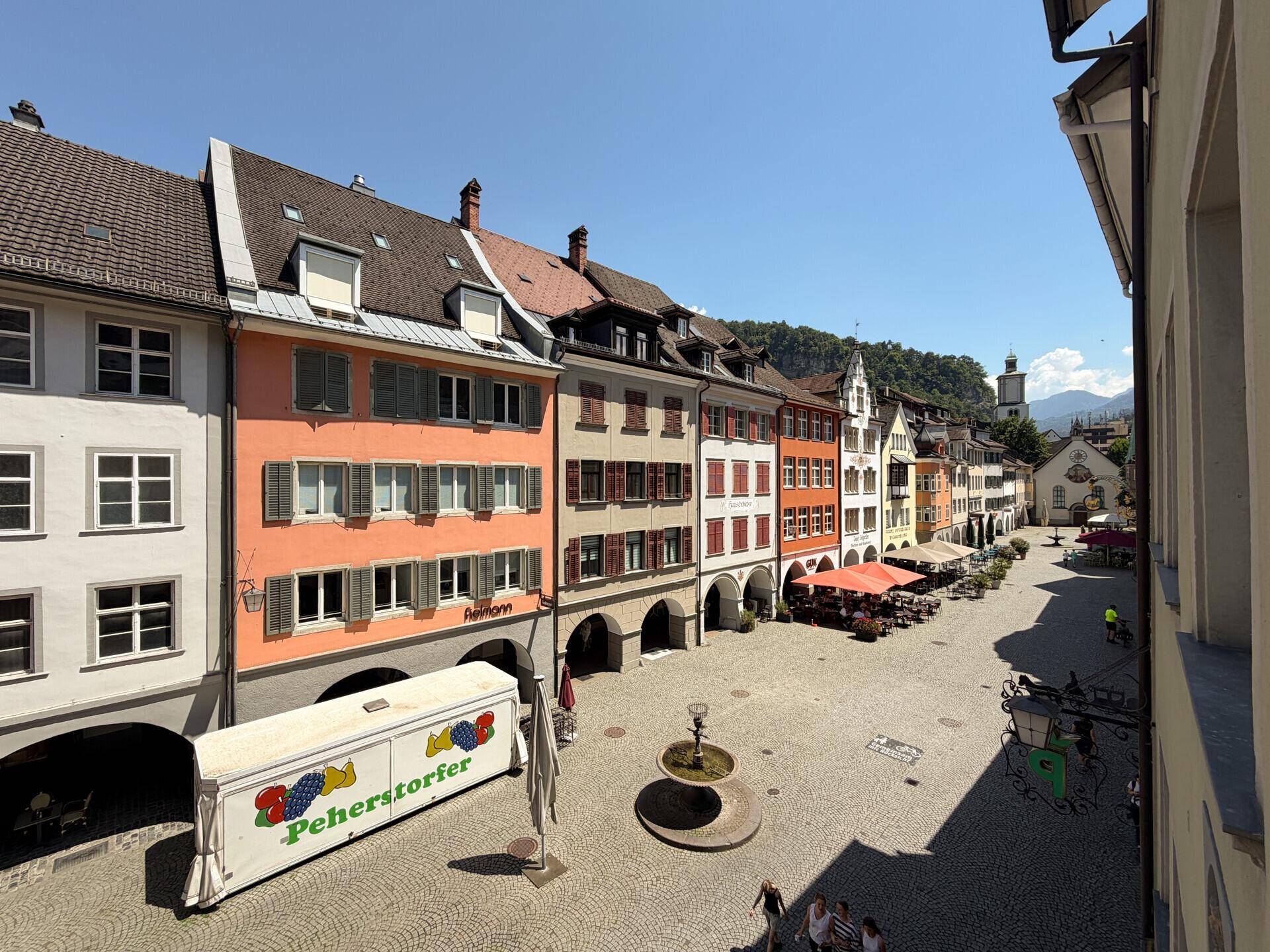 Malerischer Blick auf einen belebten Stadtplatz mit historischen Gebäuden und Cafés.