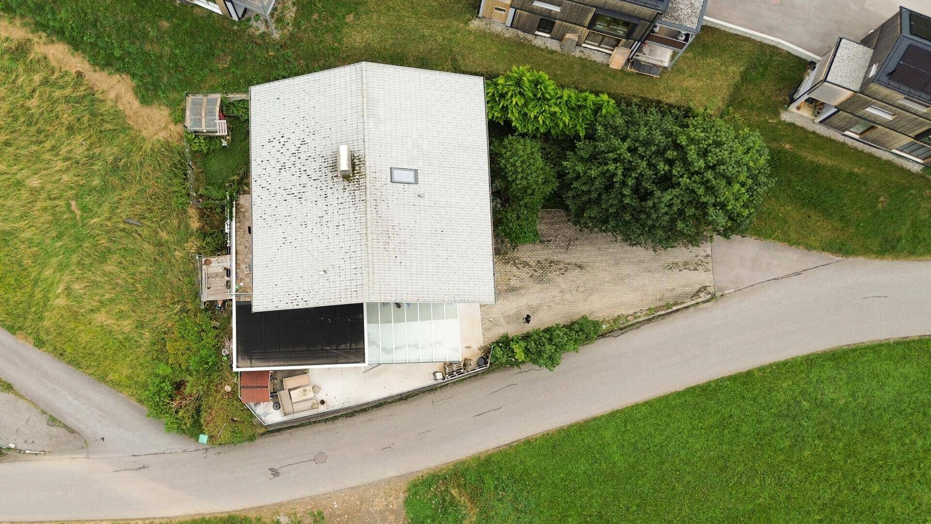 Draufsicht auf das Haus mit Dach, Carport und angrenzenden Grünflächen und Wegen.