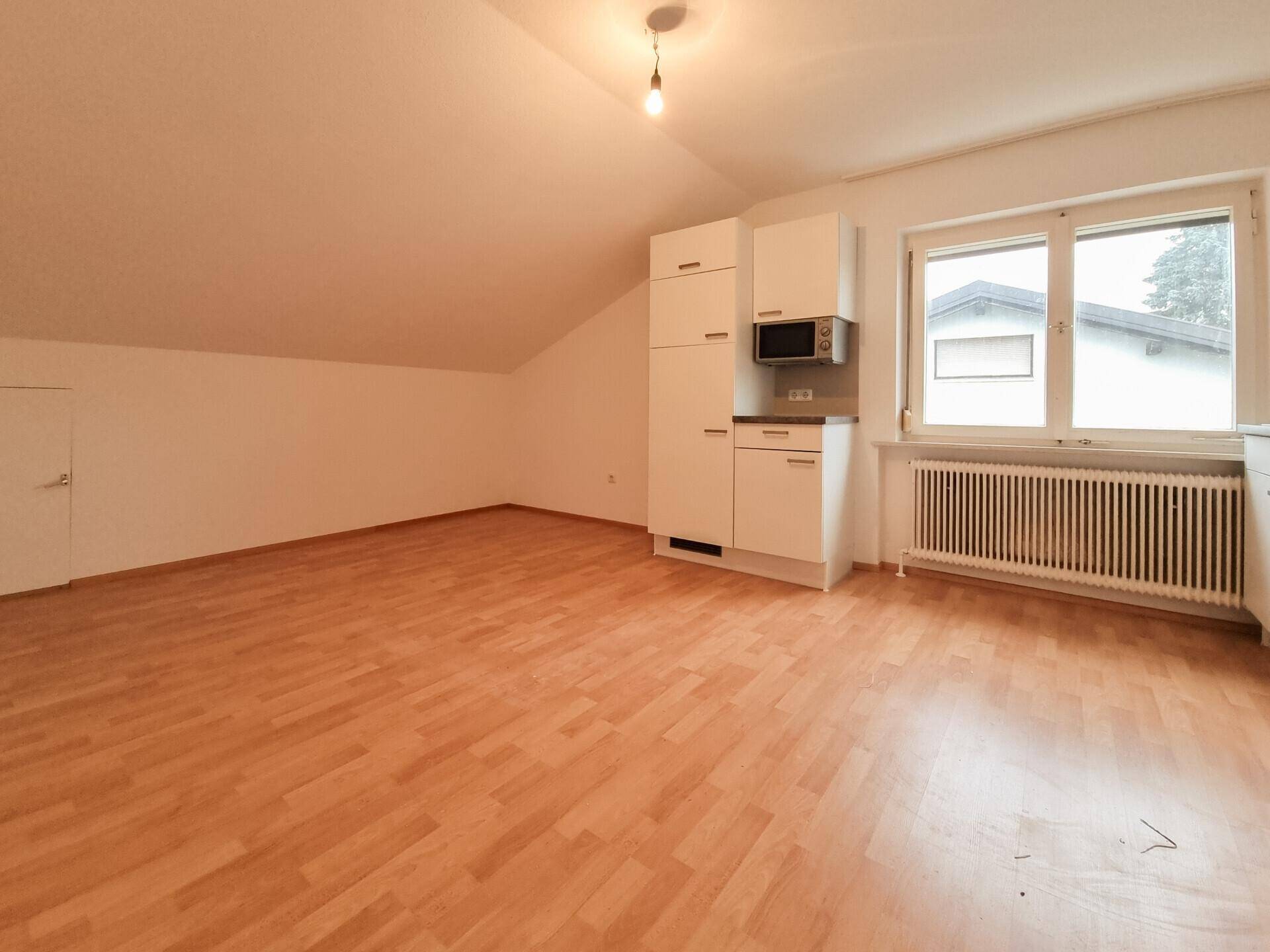 Kompakte Küchenzeile mit Mikrowelle und Kühlschrank in einem hellen Raum mit Fenster.