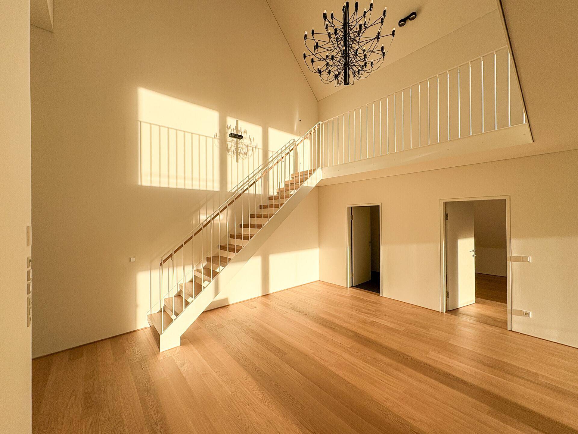 Geräumiger Wohnbereich mit offener Holztreppe zur Galerie und viel natürlichem Lichteinfall.