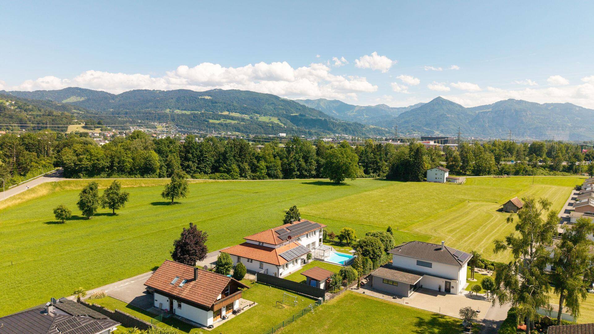 Weitläufige Luftaufnahme des Anwesens mit Pool, umgeben von grünen Feldern und Bergblick.